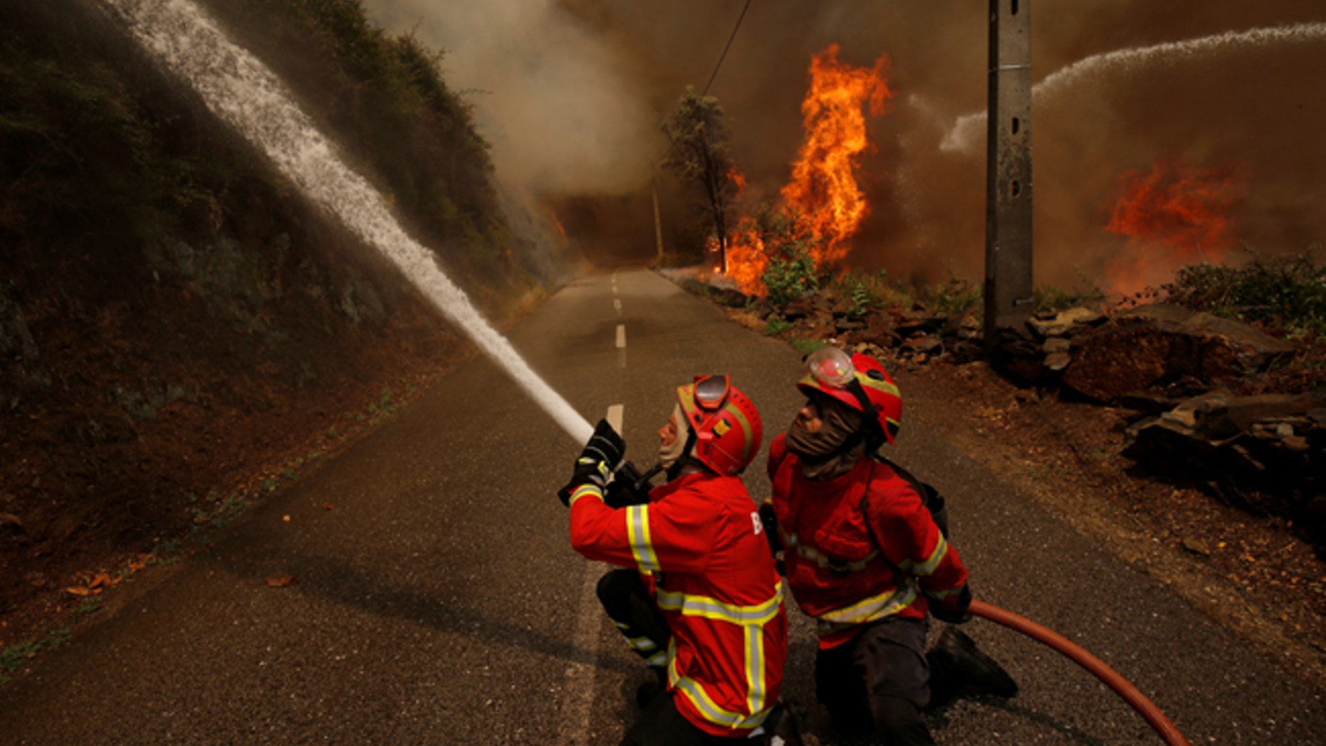 Firefighters work to put out a forest fire in the village of Sandinha, near Gois, Portugal, June 20, 2017. REUTERS/Rafael Marchante - RTS17VXR
