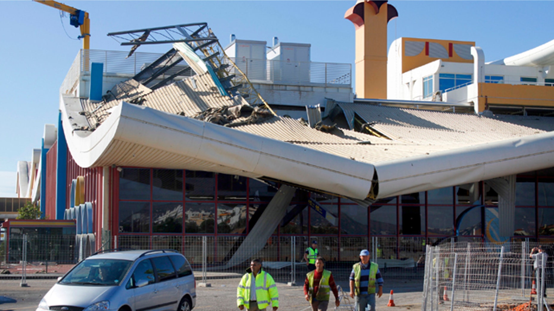 Oct. 24, 2011: Workers walk in front of the damaged building of Faro airport.