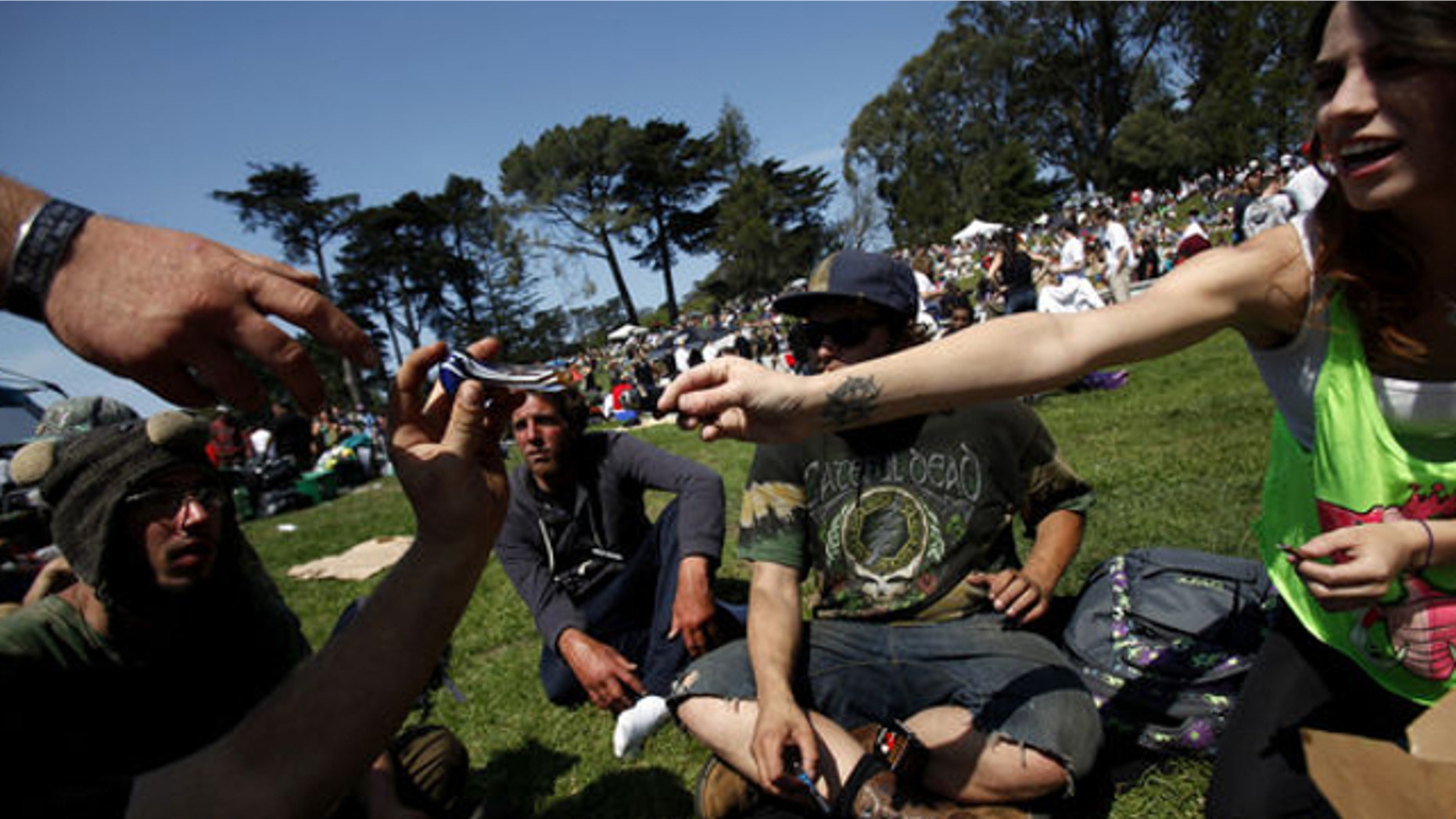 April 20, 2014: Jessica Morales, far right, passes a pipe to Brian Strelow, hand at left, during 420 celebrations at Hippie Hill in Golden Gate Park in San Francisco, Calif.