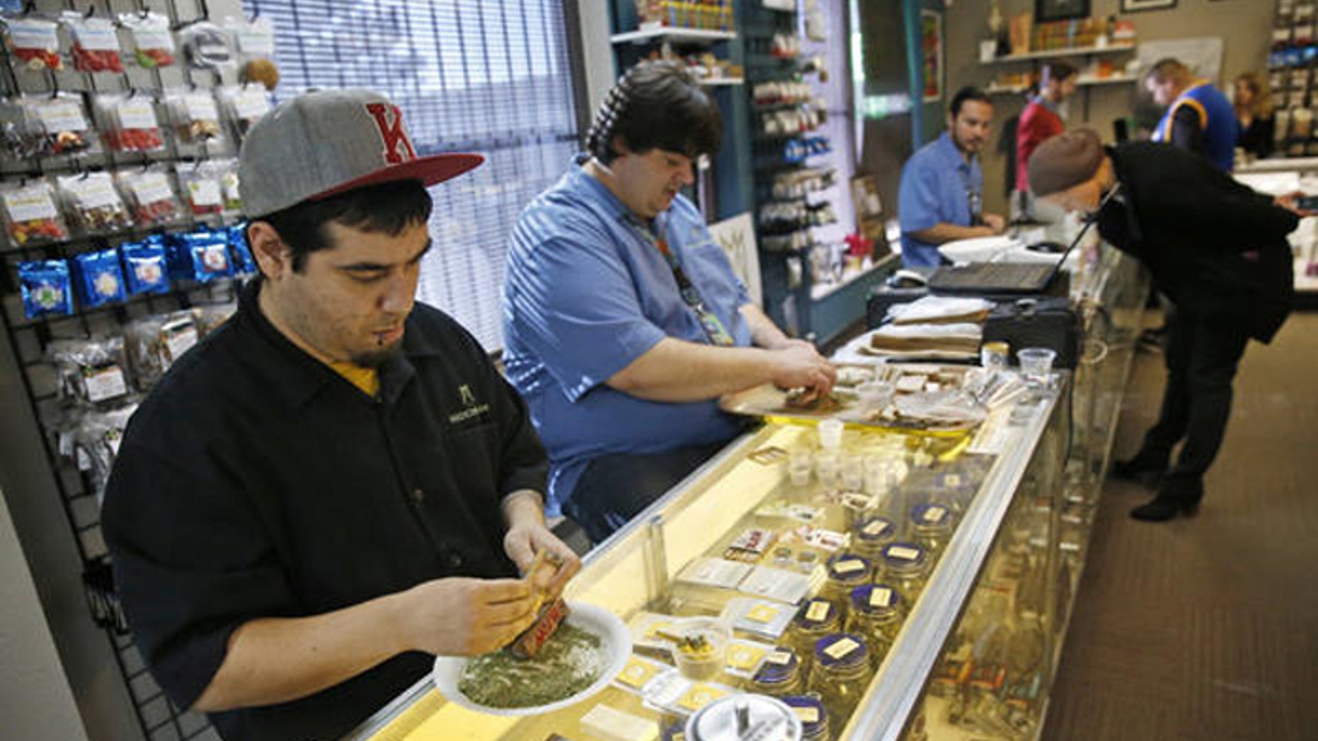 Employees roll joints behind the sales counter at Medicine Man marijuana dispensary in Denver. (AP)