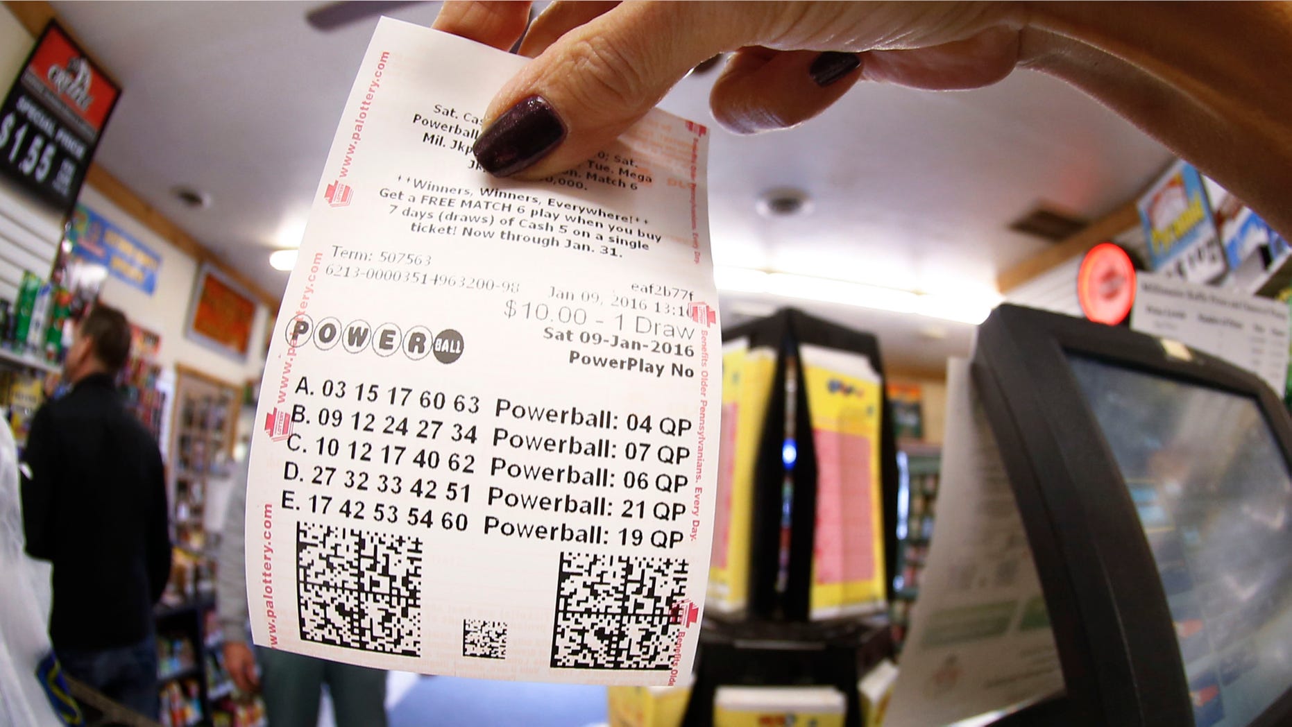 In this photo made with a fisheye lens a clerk hands a patron his $10 worth of chances for the upcoming Powerball drawing on Saturday, Jan. 9, 2016, in Cranberry Township, Pa. The Powerball jackpot has reached a record $900 million, with the drawing Saturday night. (AP Photo/Keith Srakocic)