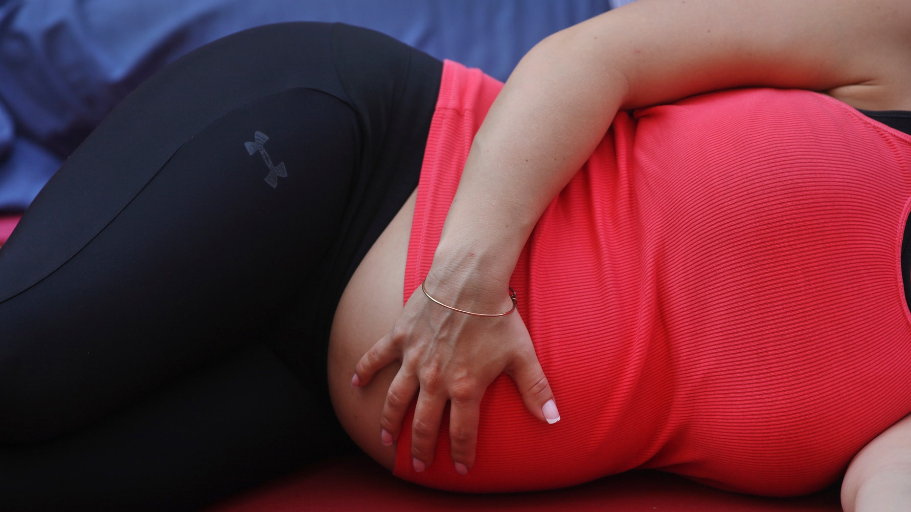 A pregnant woman touches her stomach as people practice yoga on the morning of the summer solstice in New York.