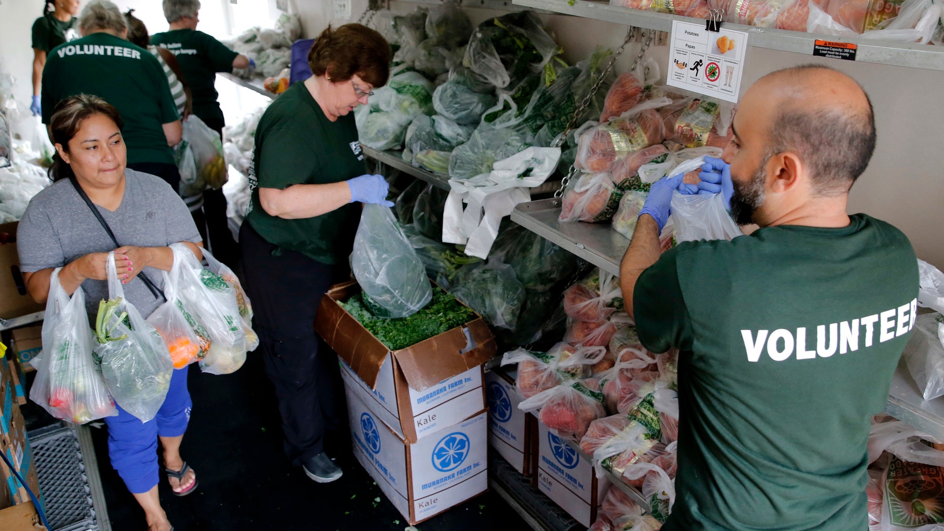 In this Sept. 22, 2016 photo, volunteers hand out fresh produce to a woman inside a refrigerator truck at Oak Forest Health Center in Oak Forest, Ill. Six health clinics are working with the Chicago food bank to host a mobile pantry filled with fresh produce. The clinics have hosted 26 'Fresh Truck' visits with the Greater Chicago Food Depository since last year, providing more than 100,000 pounds of fresh fruits and vegetables to more than 3,200 households.