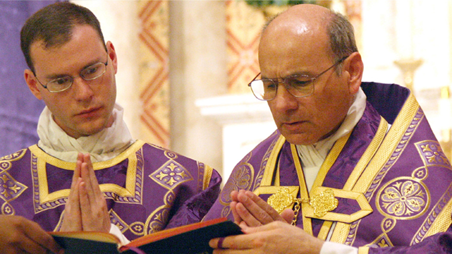 June 11, 2014: In this photo provided by The Catholic Sun, date not known, the Rev. Kenneth Walker, left, and the Rev. Joseph Terra perform a Mass in Phoenix. Walker was killed and Terra was critically injured during a robbery attempt at Mother of Mercy Mission church.