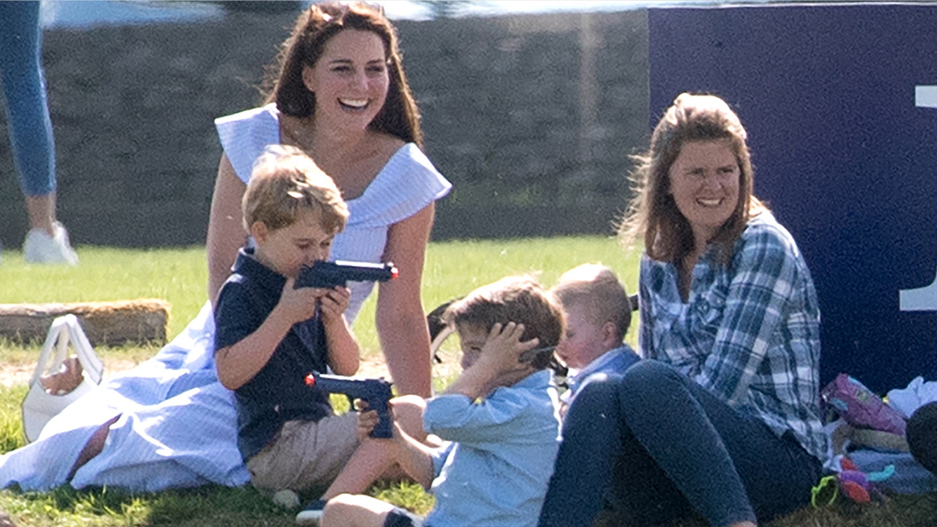 Prince George, in the dark navy shirt, plays with a toy gun as mom Kate Middleton laughts at a polo game at Beaufort Polo Club.
Pictured: Catherine,the Duchess of Cambridge and Prince George