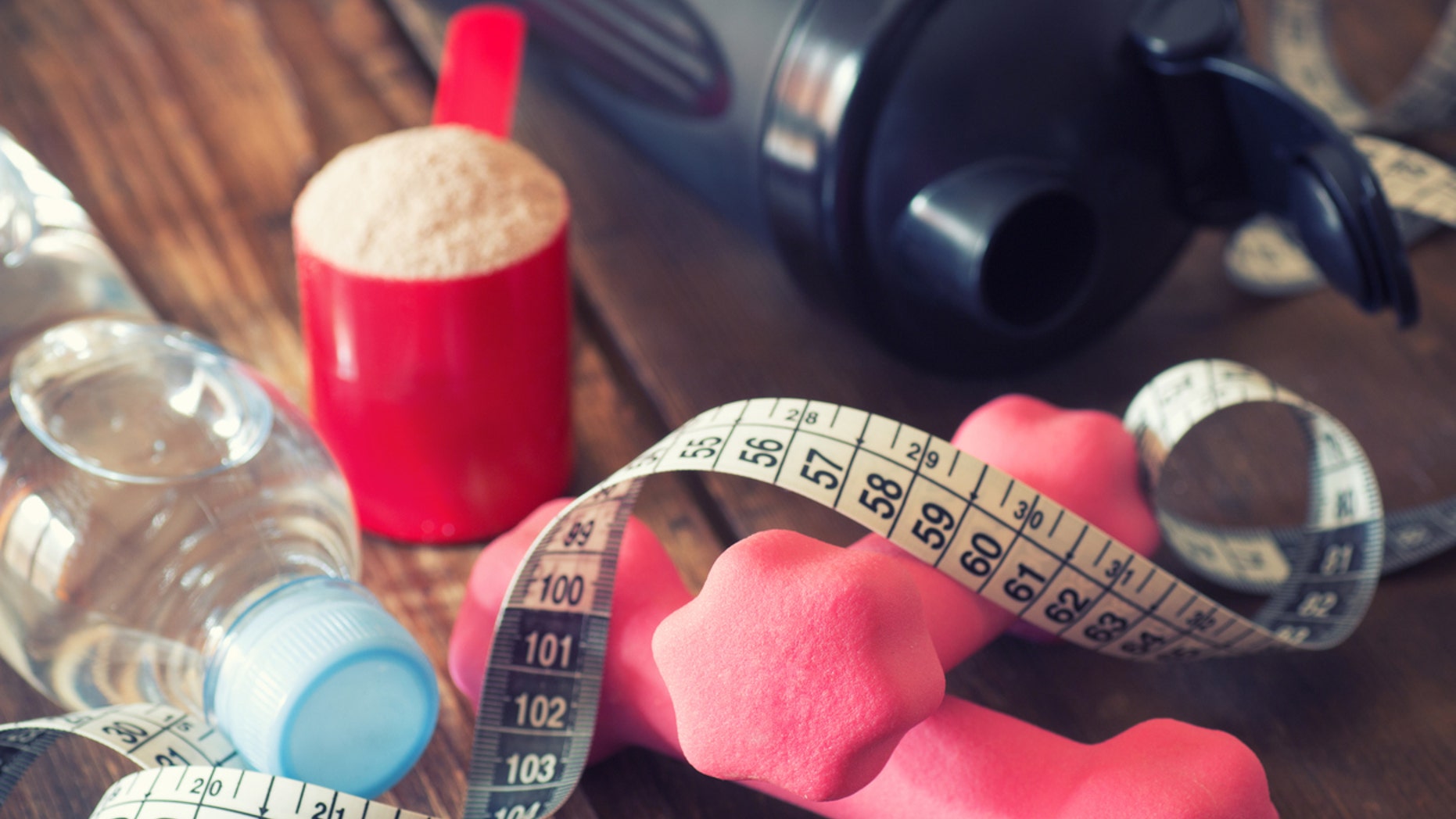 weight loss concept with tape measure whey powder, pink dumbbells and black shaker