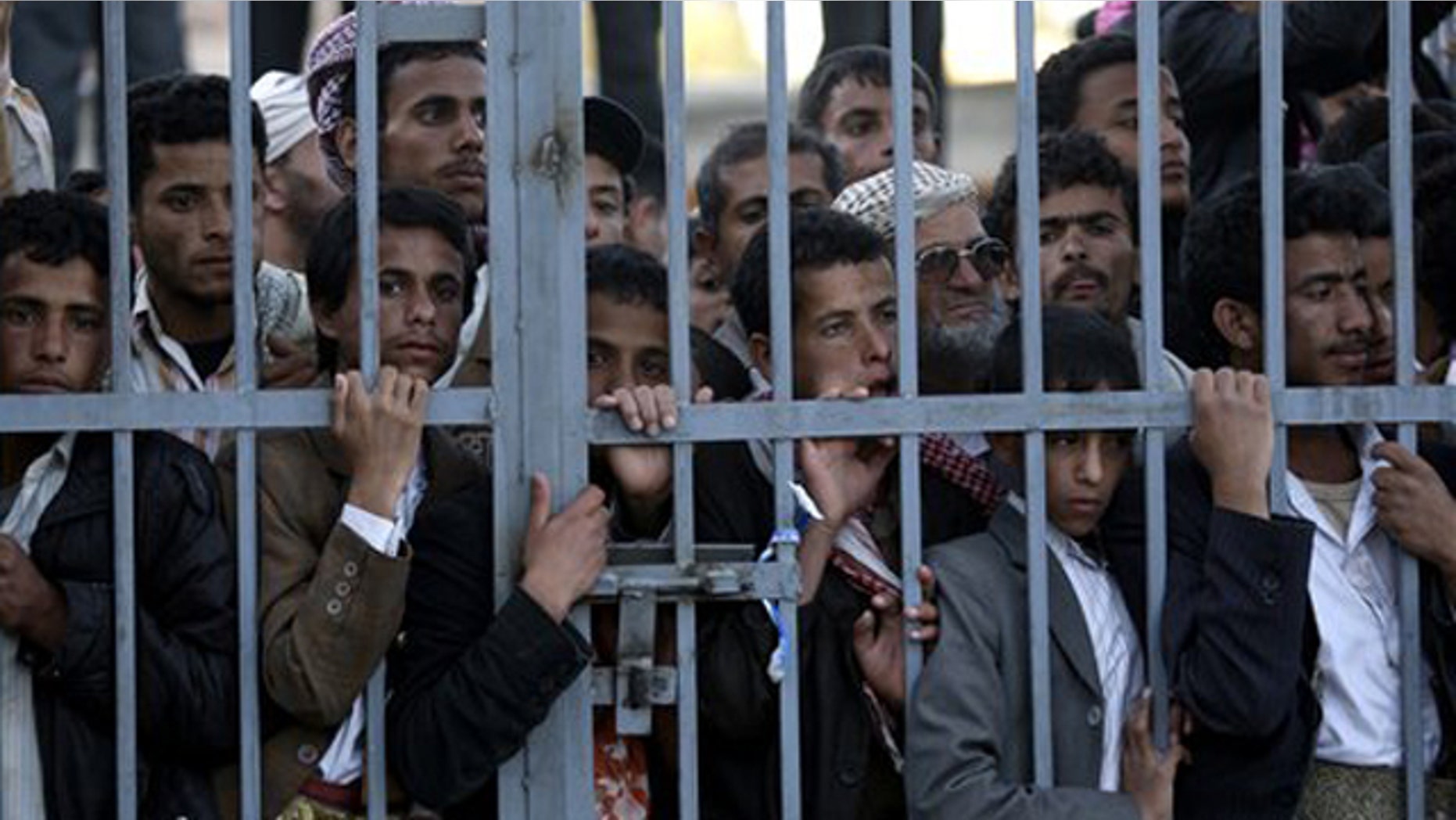 Dec. 24, 2011: Protestors stand behind the gate of a field hospital to watch wounded demonstrators being carried from the site of clashes with security forces, in Sanaa, Yemen.