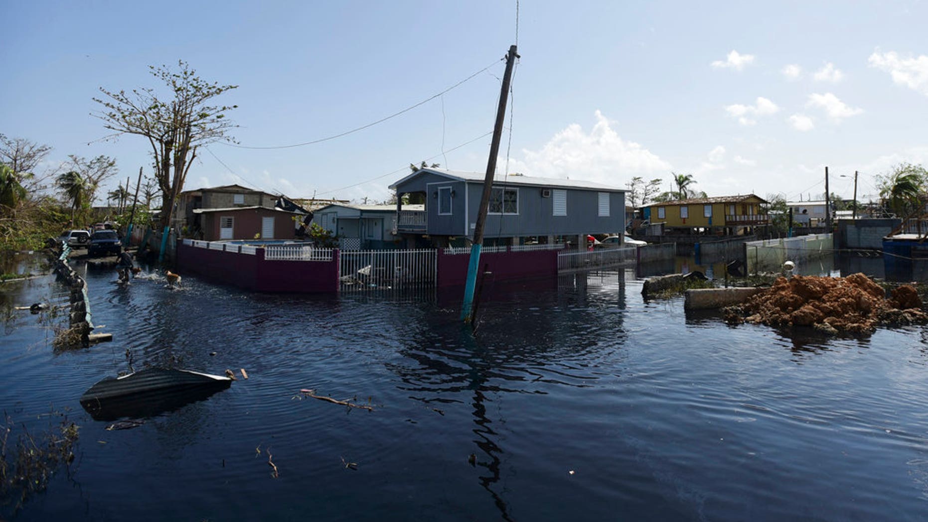 Homes in the Juana Matos community are surrounded by flood waters in Catano, Puerto Rico, Thursday, Sept. 28, 2017, one week after the passage of Hurricane Maria. The aftermath of the powerful storm has resulted in a near-total shutdown of the U.S. territoryâs economy that could last for weeks and has many people running seriously low on cash and worrying that it will become even harder to survive on this storm-ravaged island. (AP Photo/Carlos Giusti)