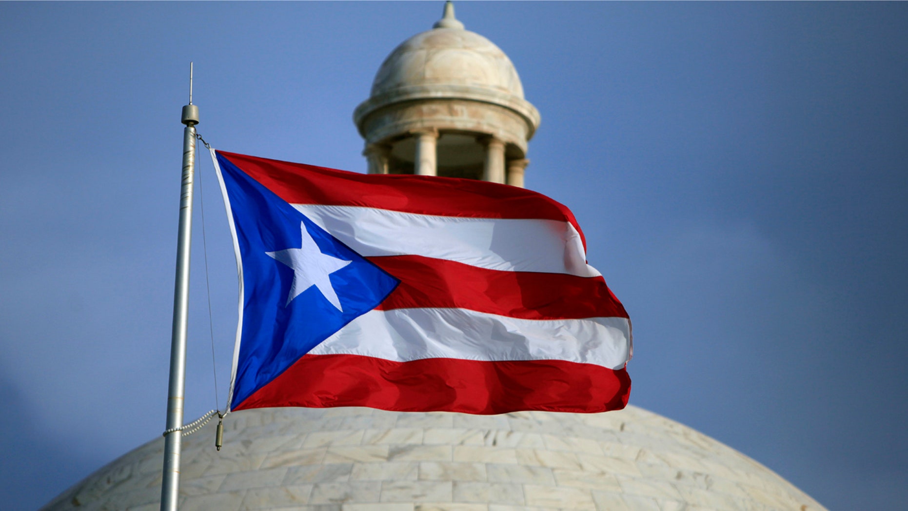 In this July 29, 2015 file photo, the Puerto Rican flag flies in front of Puerto Rico's Capitol as in San Juan, Puerto Rico.