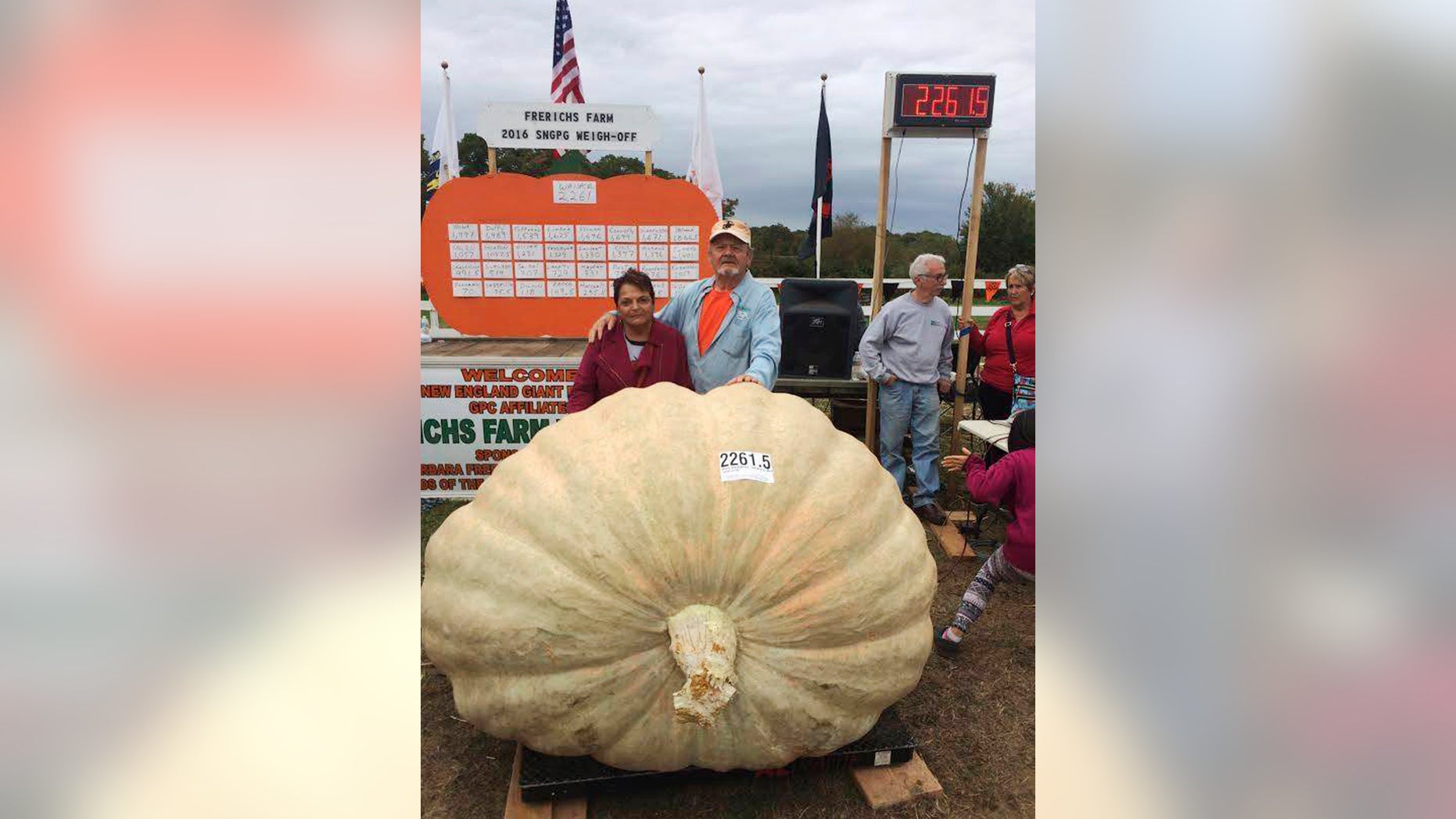 In this Oct. 8, 2016 photo provided by Ron Wallace, Richard and Catherine Wallace stand with a 2,261.5-pound pumpkin that Richard grew to set the North American giant pumpkin record at the Frerichs Farm Pumpkin Weigh Off in Warren, R.I.