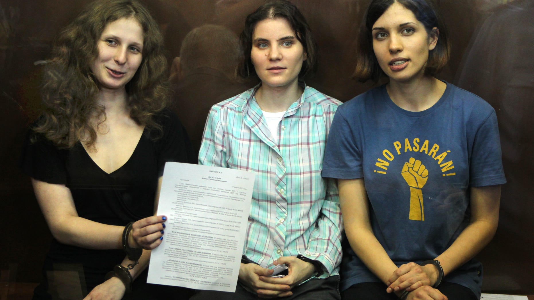 Aug 17, 2012: Feminist punk group Pussy Riot members, from left, Maria Alekhina, Yekaterina Samutsevich, and Nadezhda Tolokonnikova show the court's verdict as they sit in a glass cage at a court room in Moscow, Russia.