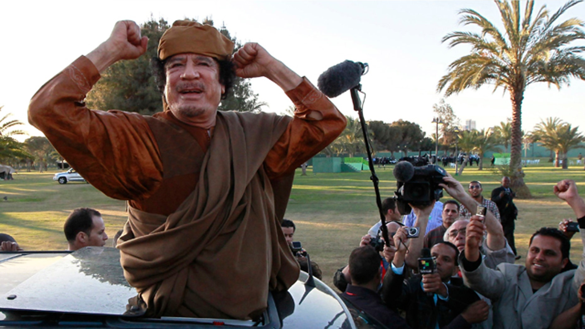 April 10, 2011: Libyan leader Moammar Qaddafi waves at his supporters people in Tripoli