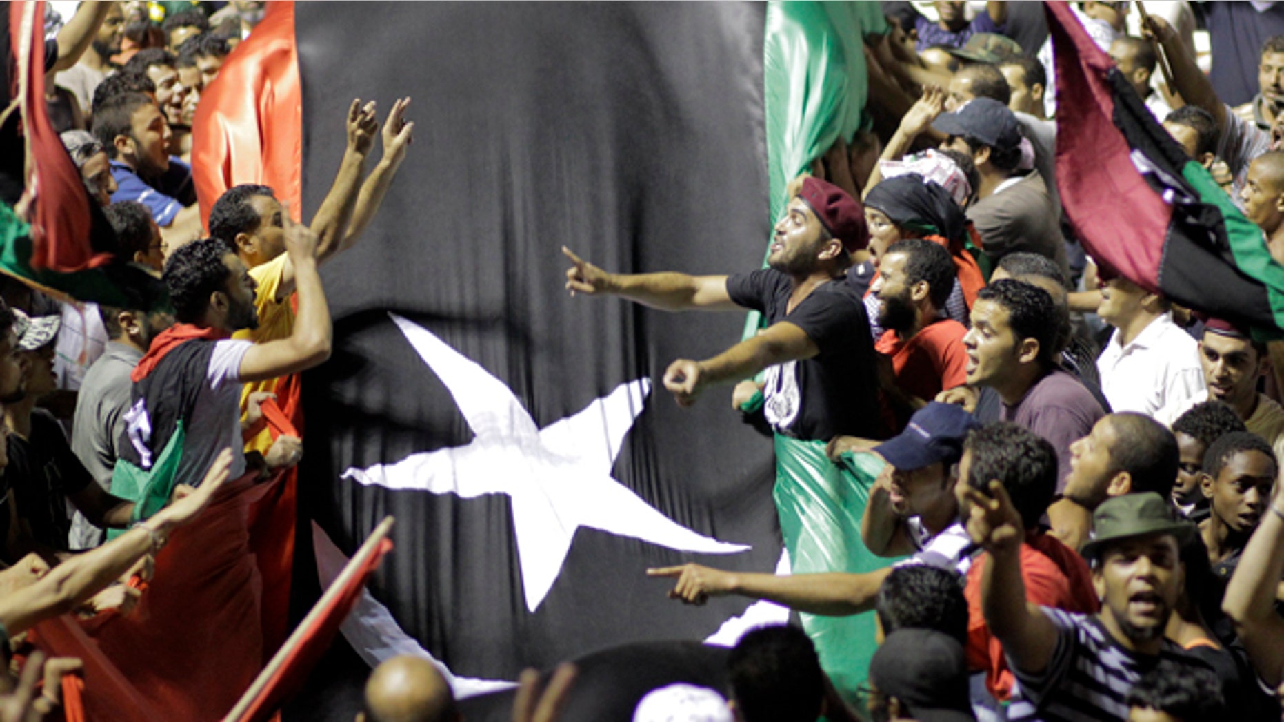 Aug. 24: Libyans holding a huge flag celebrate overrunning Muammar Qaddafi's main compound Bab al-Aziziya in Tripoli, Libya. Hundreds of Libyan rebels stormed Qaddafi's compound Tuesday, charging wildly through the symbolic heart of the crumbling regime as they killed loyalist troops, looted armories and knocked the head off a statue of the besieged dictator.