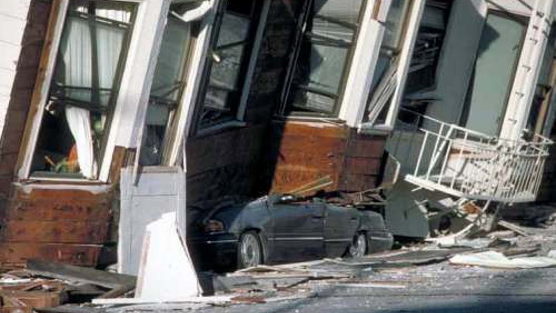 An automobile lies crushed under the third story of this apartment building in the Marina District, California, from the Loma Prieta earthquake in 1989.