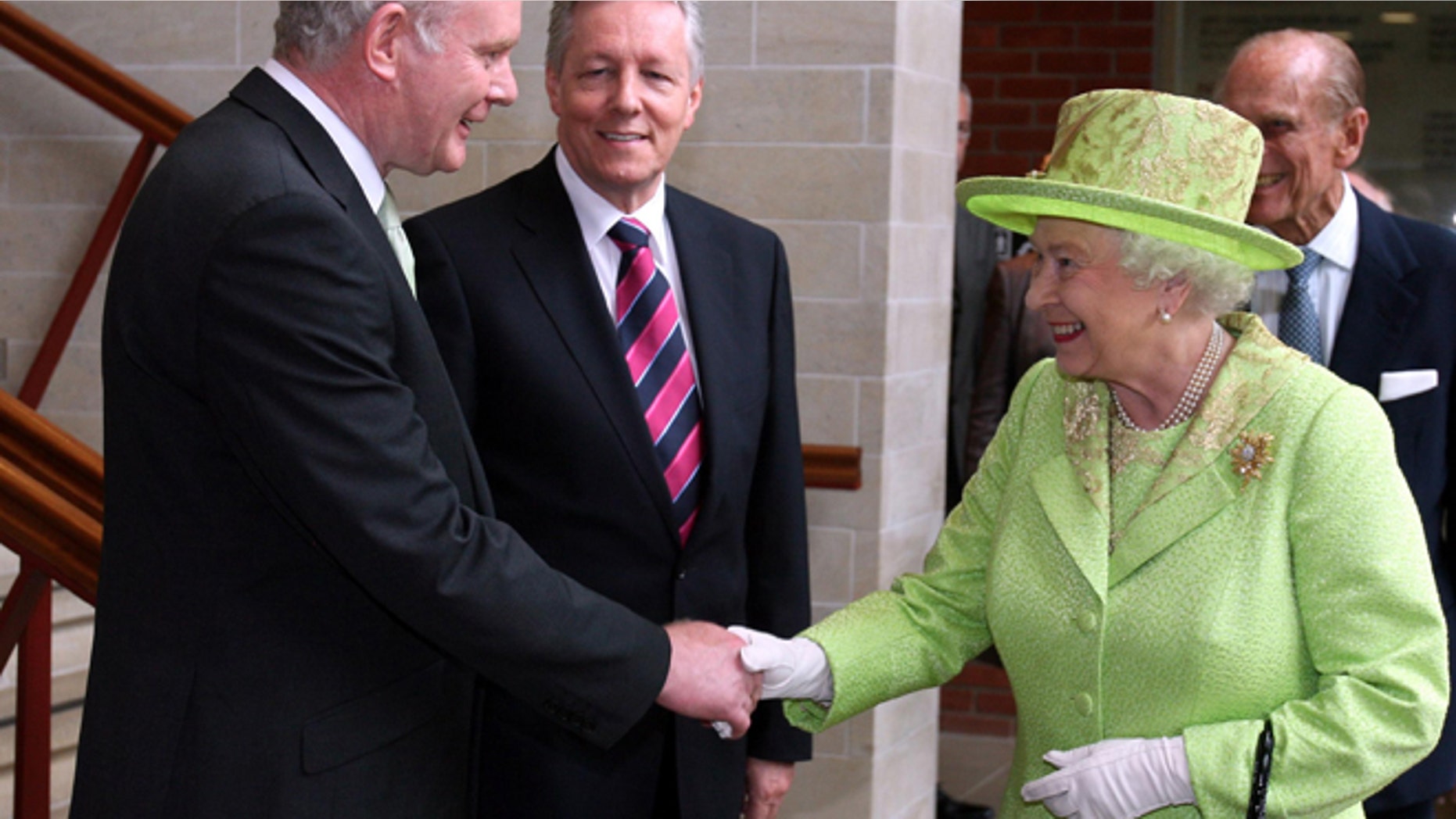 June 27, 2012: Britain's Queen Elizabeth II shakes hands with Northern Ireland Deputy First Minister and former IRA commander Martin McGuinness watched by First minister Peter Robinson, centre, at the Lyric Theatre in Belfast, Northern Ireland.