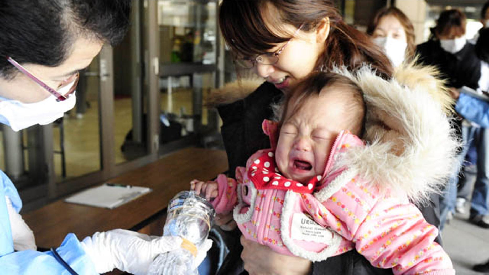 March 17: A baby cries as she is helped by her mother to be screened for radiation exposure before entering an evacuation center in Fukushima, northern Japan. (AP/Kyodo News)