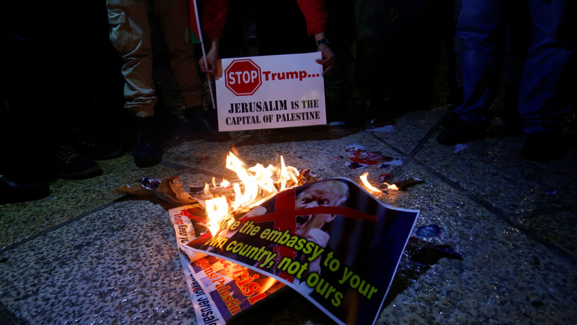Palestinian burn a poster of the U.S. President Donald Trump during a protest in Bethlehem, West Bank, Wednesday, Dec. 6, 2017. Defying dire, worldwide warnings, President Donald Trump on Wednesday broke with decades of U.S. and international policy by recognizing Jerusalem as Israel's capital.(AP Photo/Nasser Shiyoukhi)