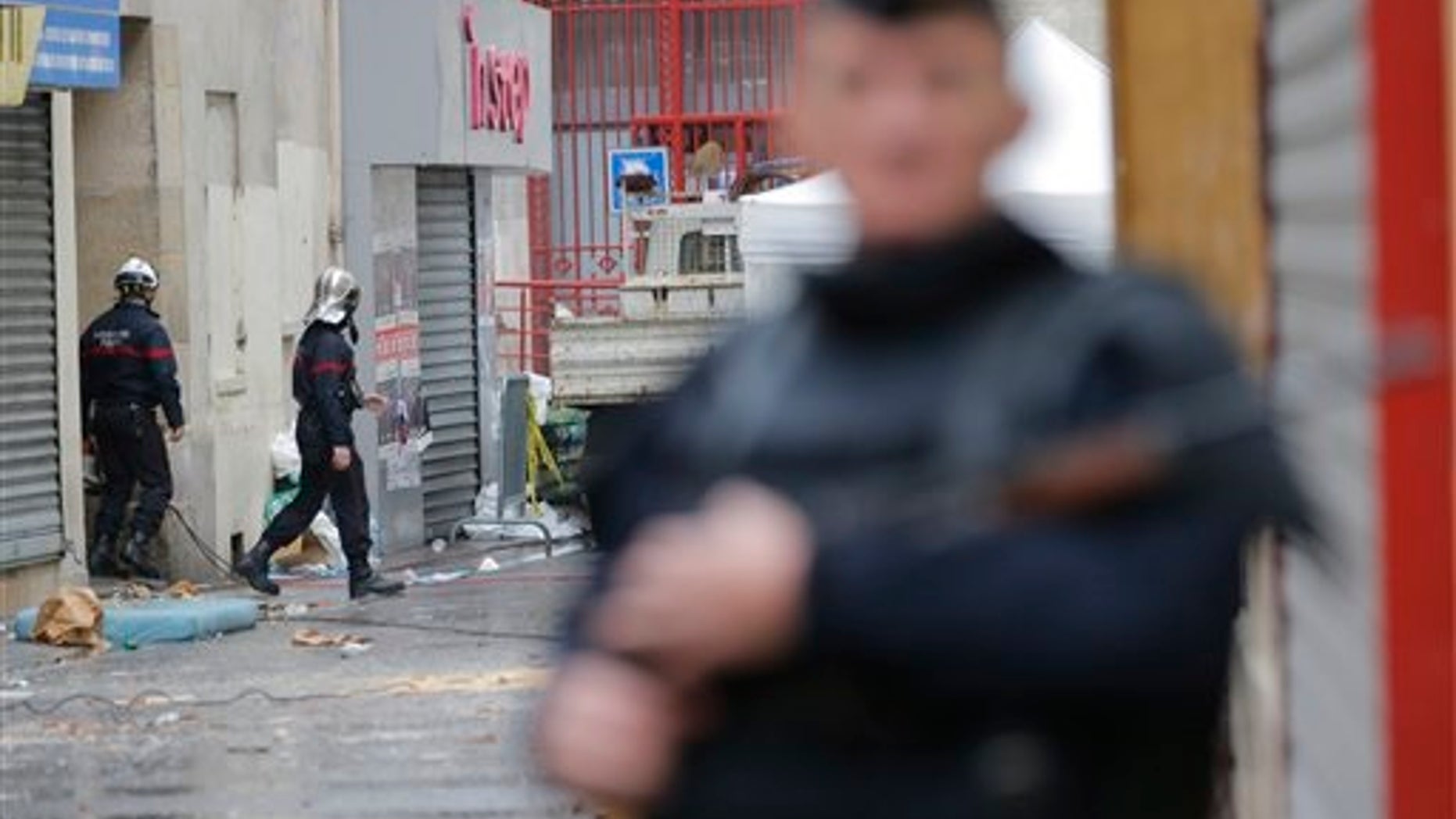 Firemen, left, leave the building of Wednesday's raid on an apartment in Paris suburb Saint-Denis, Thursday Nov.19, 2015. With France still reeling from last week's deadly attacks in Paris, Prime Minister Manuel Valls warned Thursday that Islamic extremists might at some point use chemical or biological weapons, and urged lawmakers to extend a national state of emergency by three months. (AP Photo/Christophe Ena)