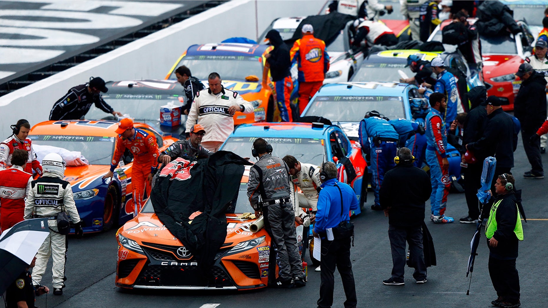 Crews cover the cars as rain falls during a NASCAR Cup Series auto race, Sunday, April 15, 2018, in Bristol, Tenn. (AP Photo/Wade Payne)