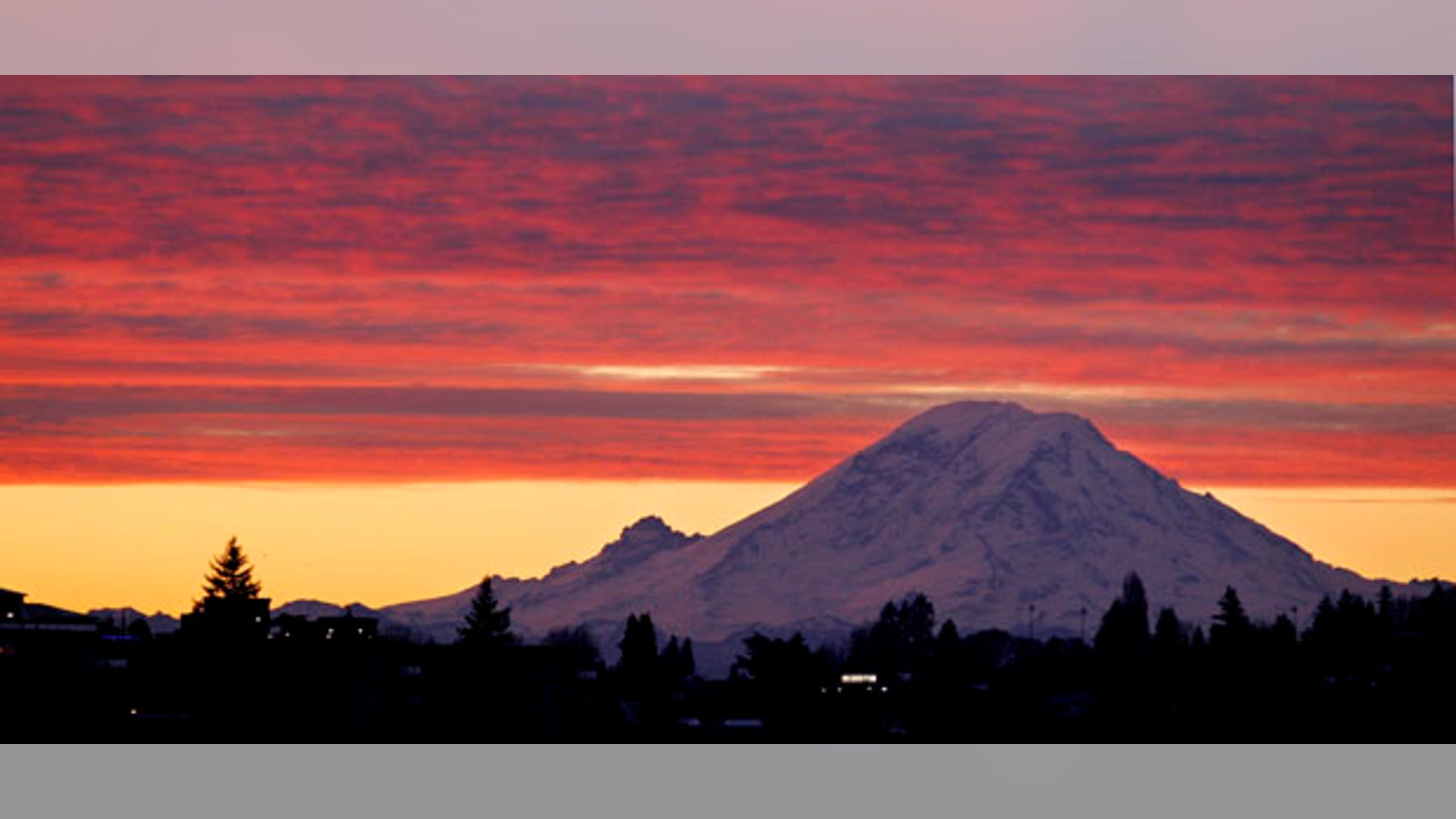 Mount Rainer, a 14,411-foot stratovolcano, is seen at dawn during a colorful sunrise Tuesday, Dec. 13, 2011, from Seattle, some 50 miles away. Generally clear skies are expected through Tuesday in the area, with an increasing chance of showers coming Wednesday, with highs in the low 40's through the week. (AP Photo/Elaine Thompson)