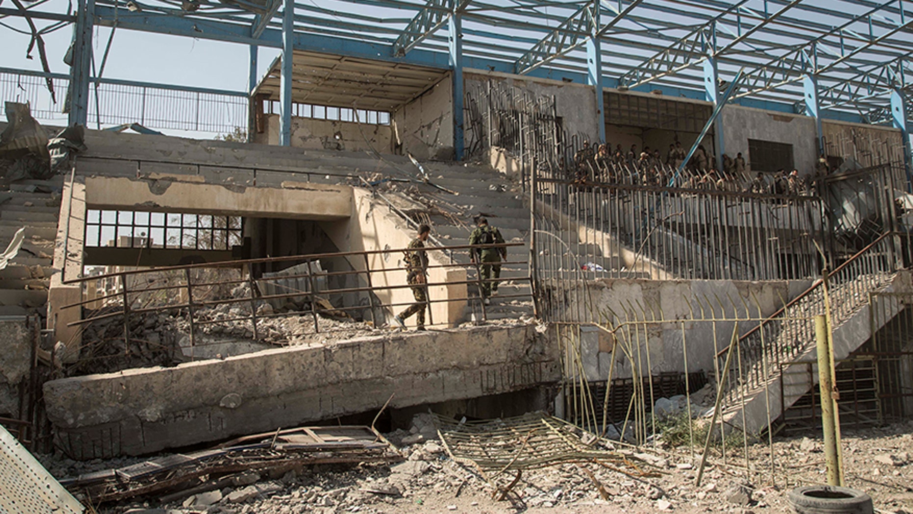 U.S.-backed Syrian fighters walk in ISIS' "Black Stadium."