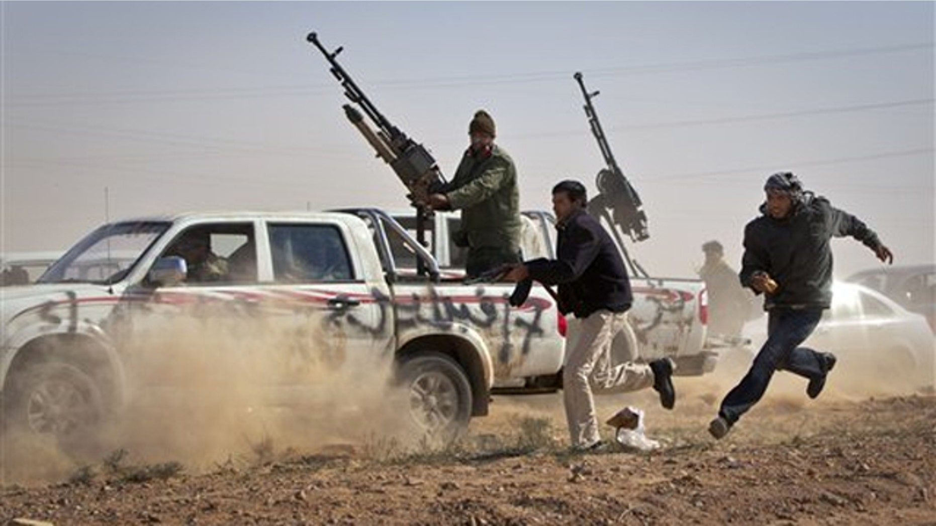 Rebel fighters shoot the tires out of a vehicle, unseen, belonging to Muammar al-Qaddafi's forces as it speeds through the rebel front line east of Brega, Libya, April 3.