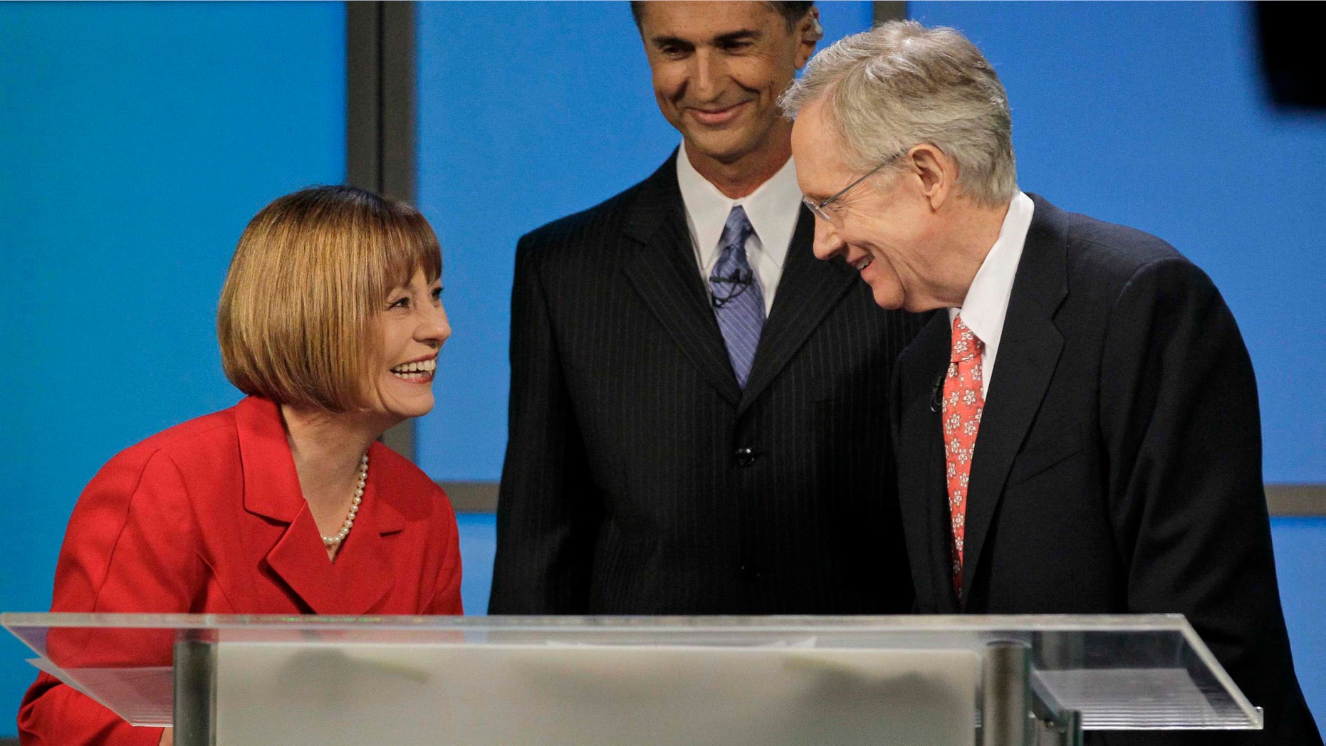 FILE - In this Oct. 14, 2010, file photo Republican Senate candidate Sharron Angle, left, and Democrat Senate Majority Leader Harry Reid talk after their televised Nevada Senate debate in Las Vegas as moderator Mitch Fox smiles. Senate races are extremely close in West Virginia and Nevada, where Reid is battling tea party-backed Angle in a bitter and costly campaign. (AP Photo/Julie Jacobson, File)