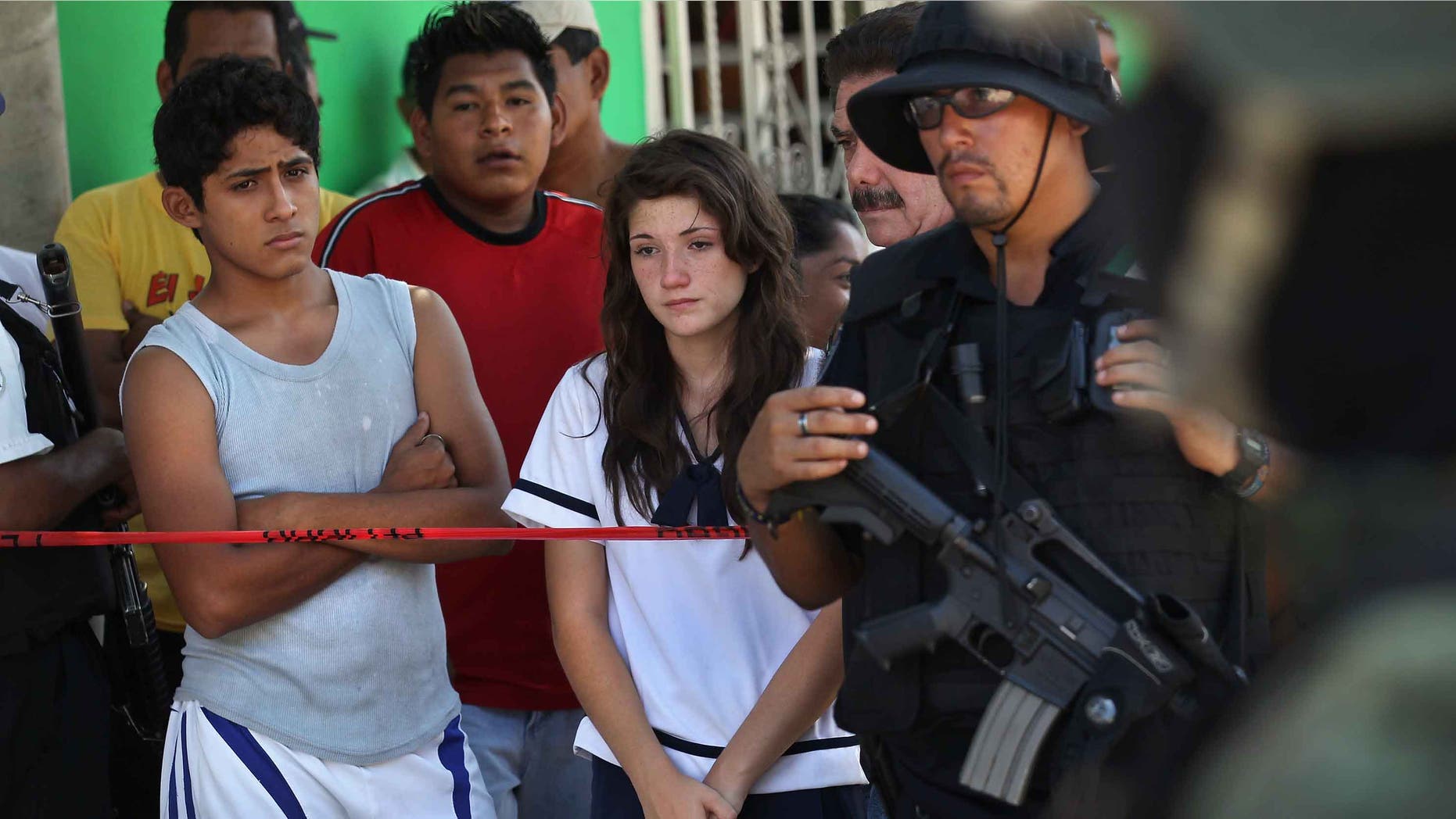ACAPULCO, MEXICO - MARCH 02: Family members, neighbors and police gather at the site of a suspected drug-related double execution on March 2, 2012 in Acapulco, Mexico. Drug violence has surged in the coastal resort in the last year, making Acapulco the second most deadly city in Mexico after Juarez. One of Mexico's top tourist destinations, Acapulco has suffered a drop in business, especially from foreign tourists, due to the violence. Toursim accounts for about 70 percent of the economy of Acapulco's state of Guerrero and 9 percent of Mexico's economy. (Photo by John Moore/Getty Images)