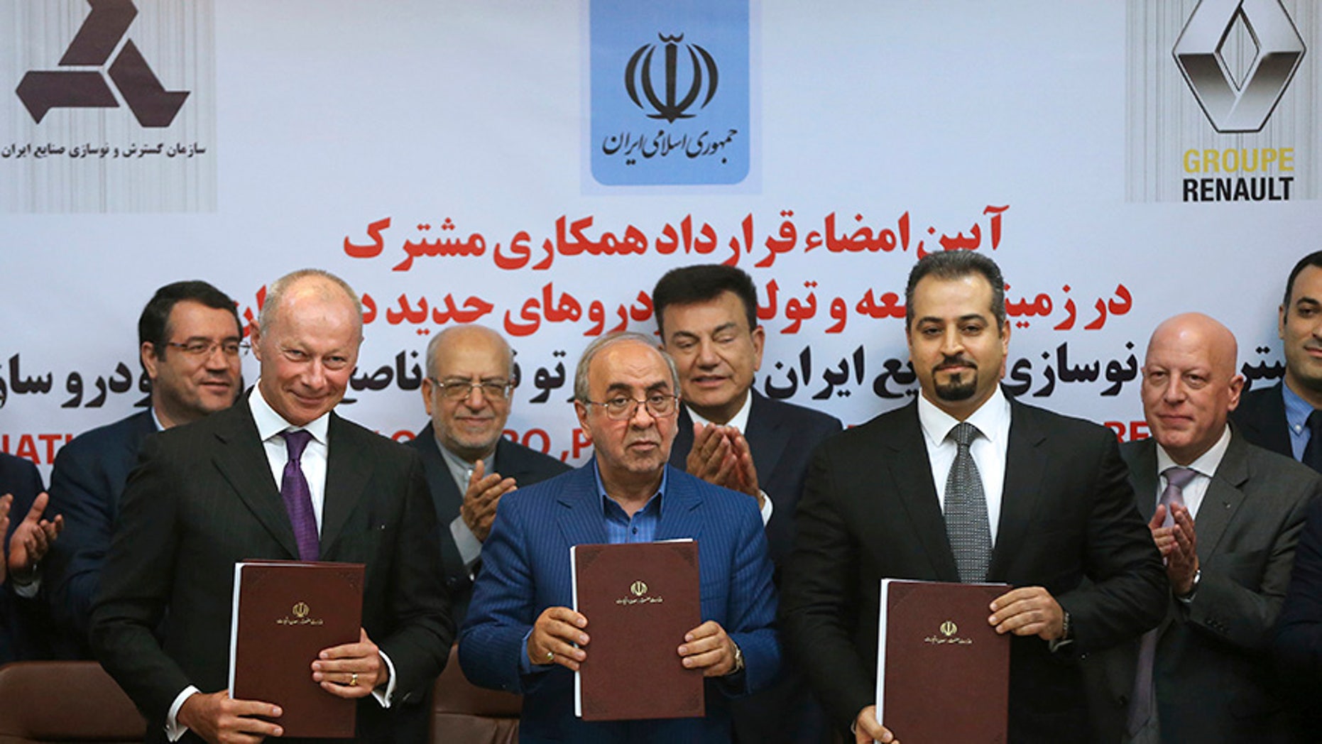 Chief Competitive Officer of Groupe Renault Thierry Bolloré, left, Chairman of Industrial Development and Renovation Oraganization of Iran, IDRO, Mansour Moazami, center, and Negin Group CEO Kourosh Morshed Solouk join shows documents to media after signing a deal in Tehran, Iran, Monday, Aug. 7, 2017. Iran signed the country's biggest-ever car deal with French multinational automobile manufacturer Groupe Renault on Monday to produce 150,000 cars, beginning in 2018. (AP Photo/Vahid Salemi)