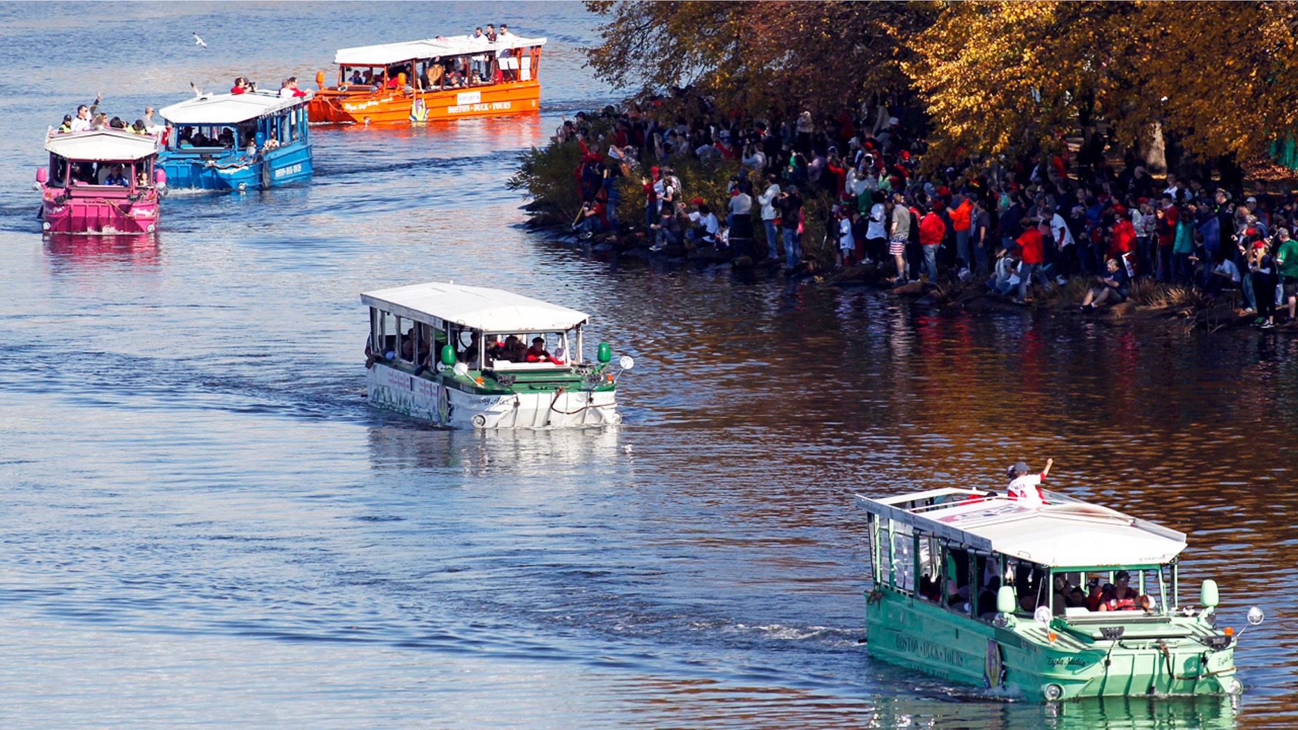 Boston Red Sox fans cheer on members of the team as they ride duck boats down the Charles River during the 2013 World Series parade and celebration.