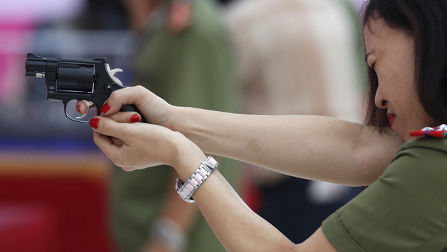 A policewoman demonstrates a Vietnamese-made pistol during celebrations to commemorate the 70th anniversary of the establishment of the Vietnam Public Security police force at the National Convention Center in Hanoi August 18, 2015. The Vietnam Police force was founded on August 19, 1945, the day of the anti-colonial people's uprising known as the August Revolution. REUTERS/Kham - RTX1OLM6