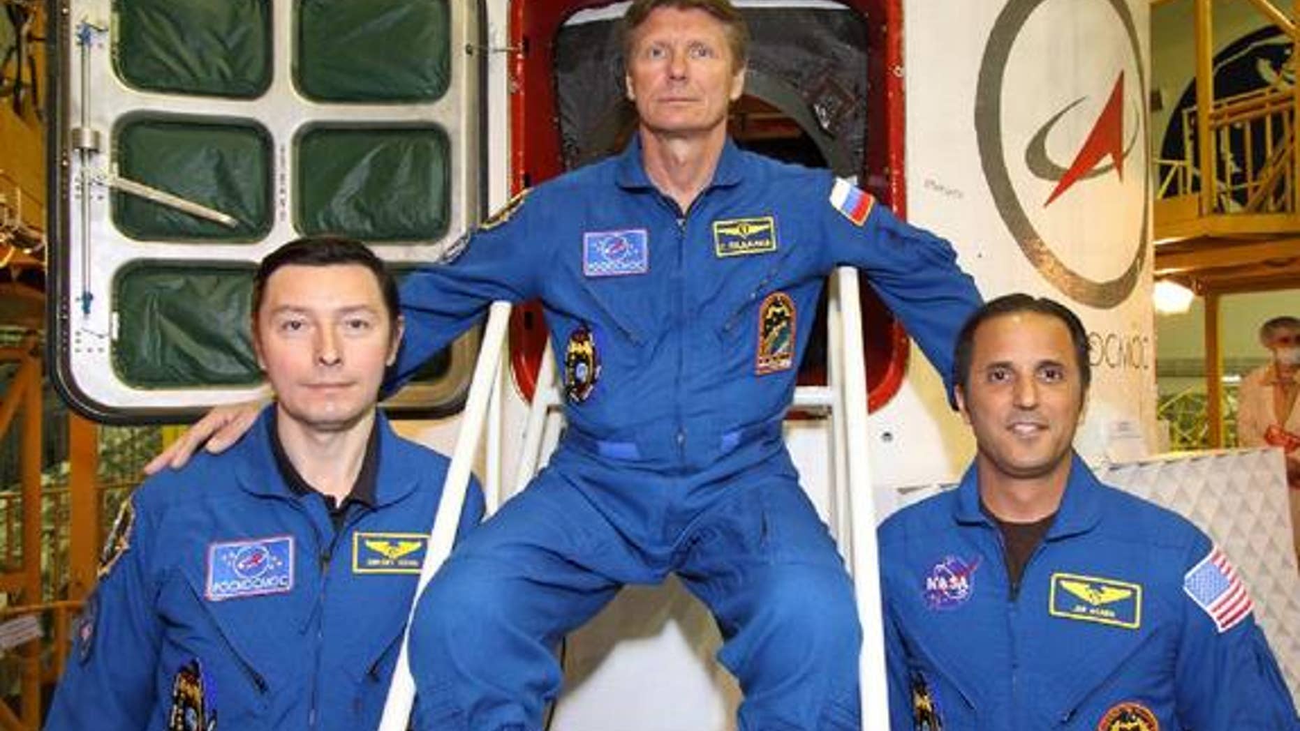 Sergei Revin (left), Gennady Padalka (center) and Joe Acaba (right) pose in front of the hatchway to their Soyuz TMA-04M spacecraft as they completed their final "fit check" inspection of the vehicle on May 11, 2012. The three will launch toward the space station on May 14.