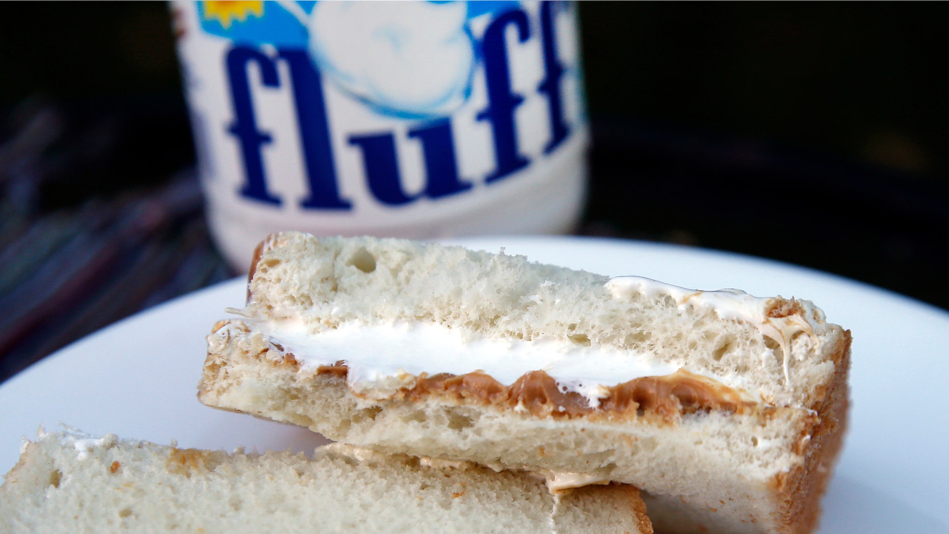 In this Sept. 27, 2013, file photo, a jar of Marshmallow Fluff and a Fluffernutter sandwich are displayed in North Andover, Mass. Archibald Query invented Fluff in 1917 in the Boston suburb of Somerville. The marshmallow concoction that's been smeared on a century's worth of sandwiches has inspired a festival and other sticky remembrances as it turns 100 in 2017. (AP Photo/Elise Amendola, File)