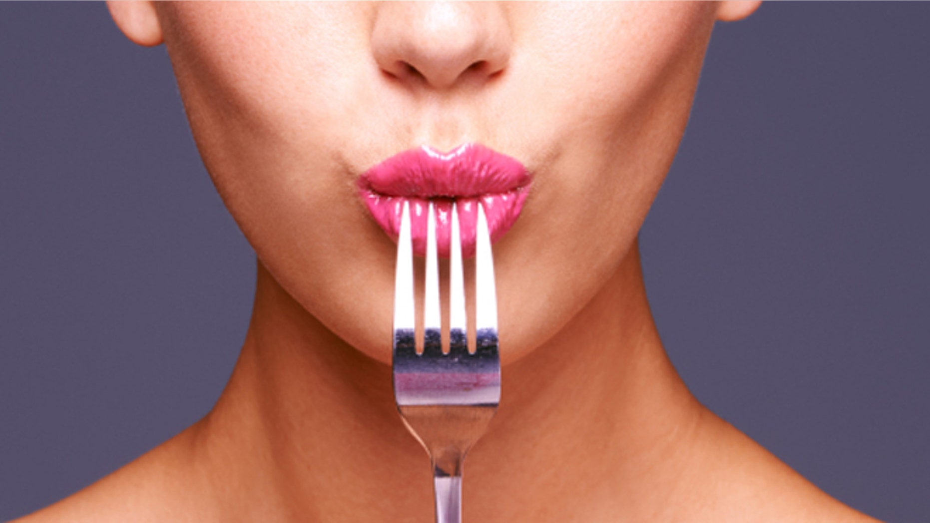 Shot of a beautiful young woman biting on a fork