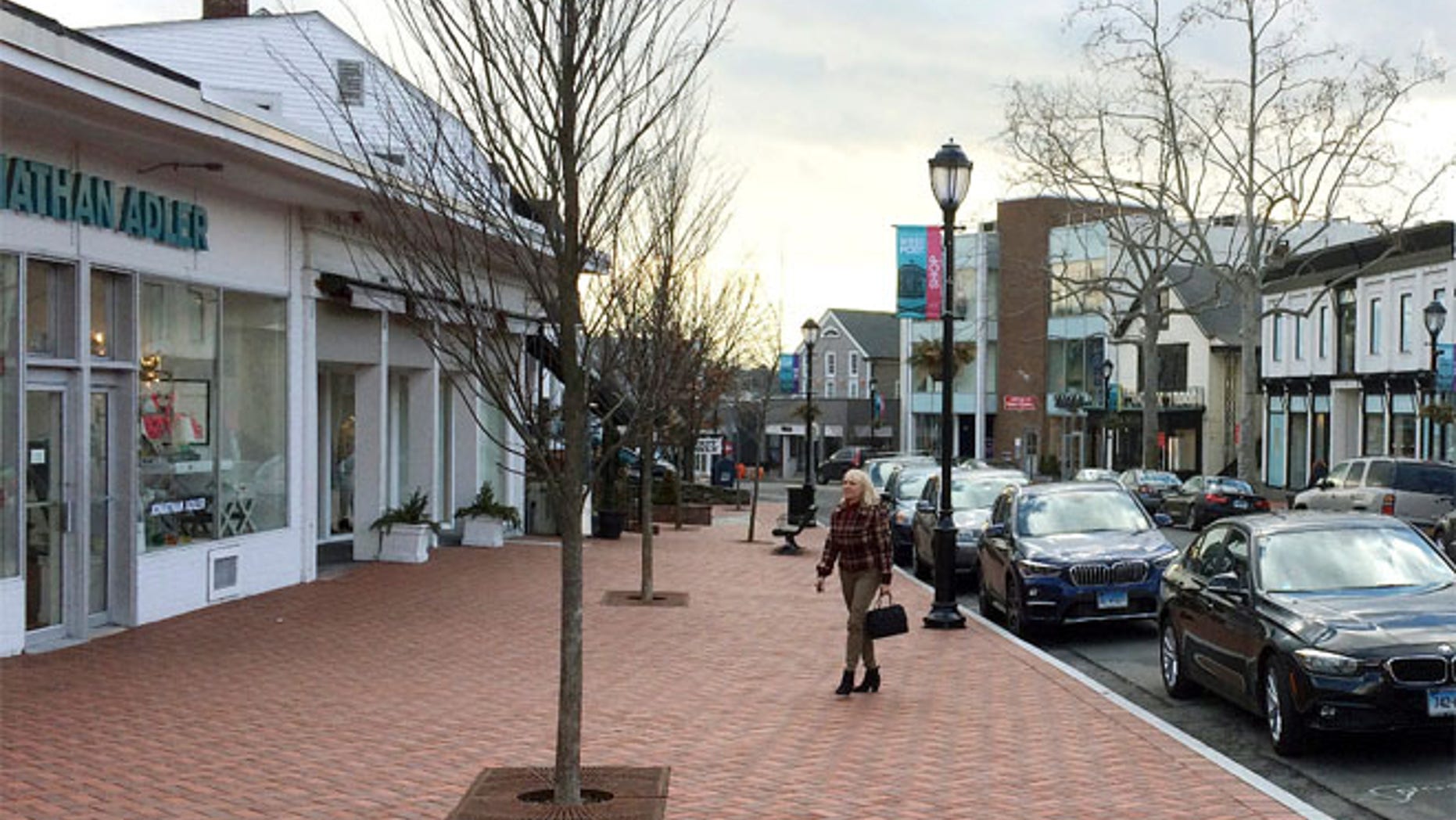 Jan. 26, 2017 photo, a woman walks near shops in downtown Westport, Conn.