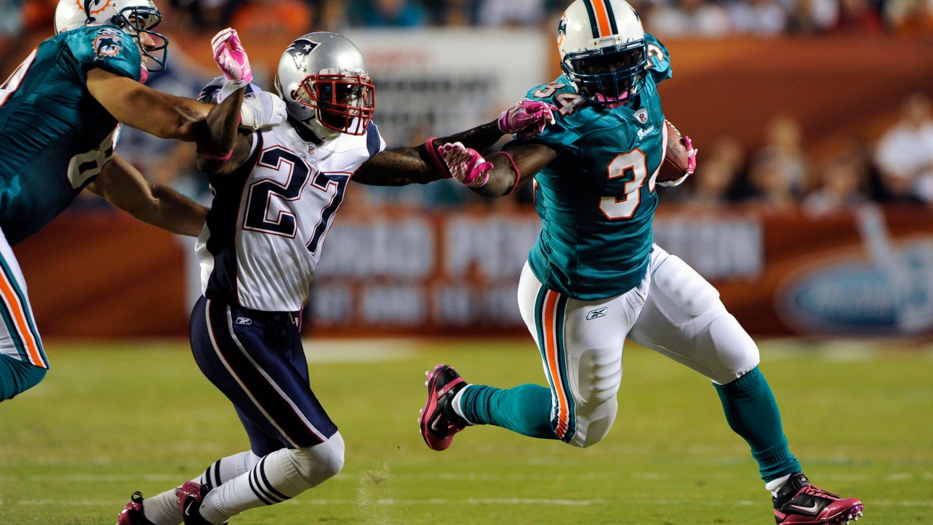 Miami Dolphins running back Ricky Williams (R) tries elude New England Patriots defender Kyle Arrington as Dolphins end Anthony Fasano (L) blocks in the first half during their NFL football game in Miami, Florida October 4, 2010. REUTERS/Hans Deryk (SPORT FOOTBALL) - RTXT1XF