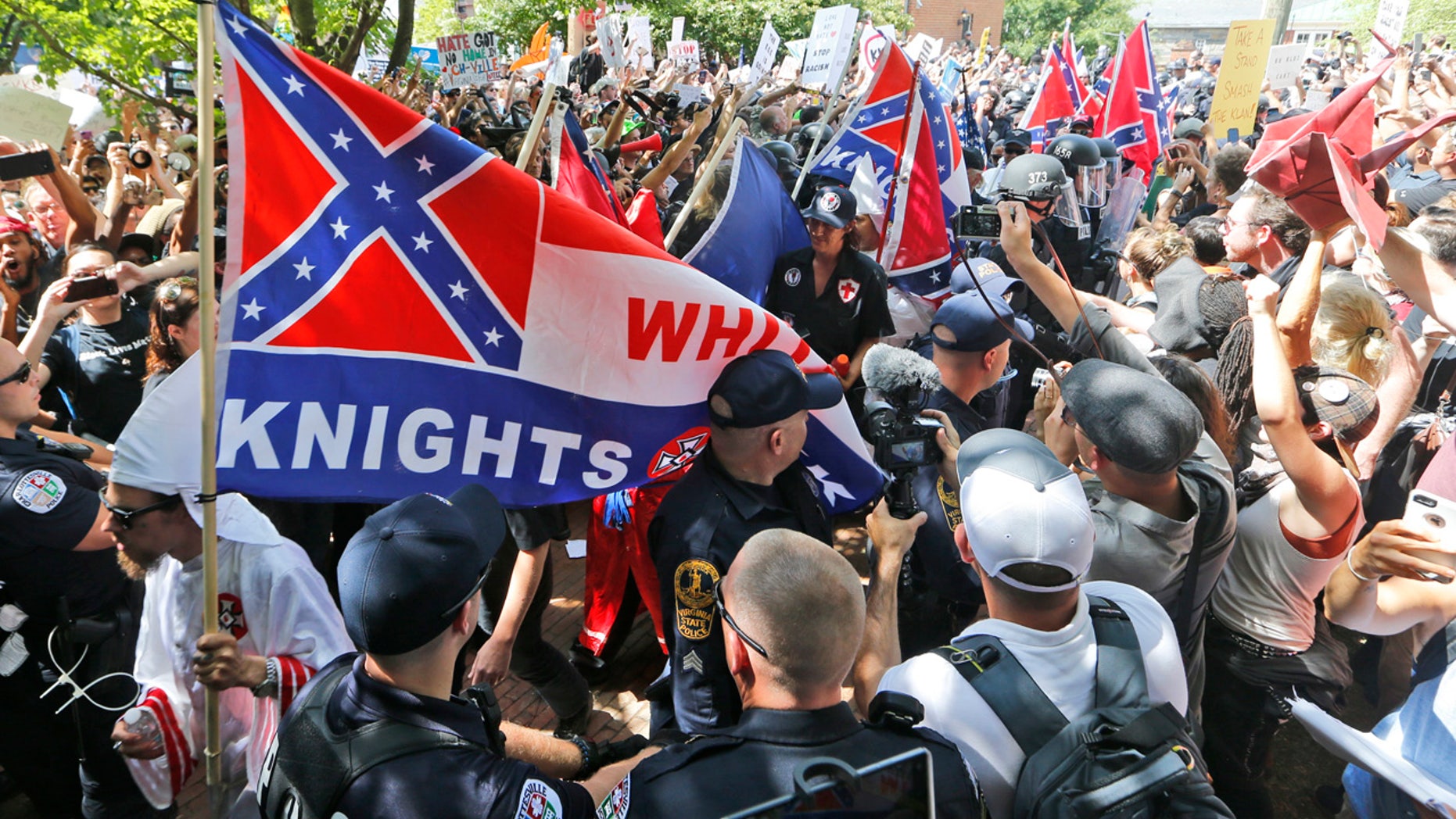 This July 8, 2017 photo shows members of the KKK escorted by police past a large group of protesters during a KKK rally in Charlottesville, Va.