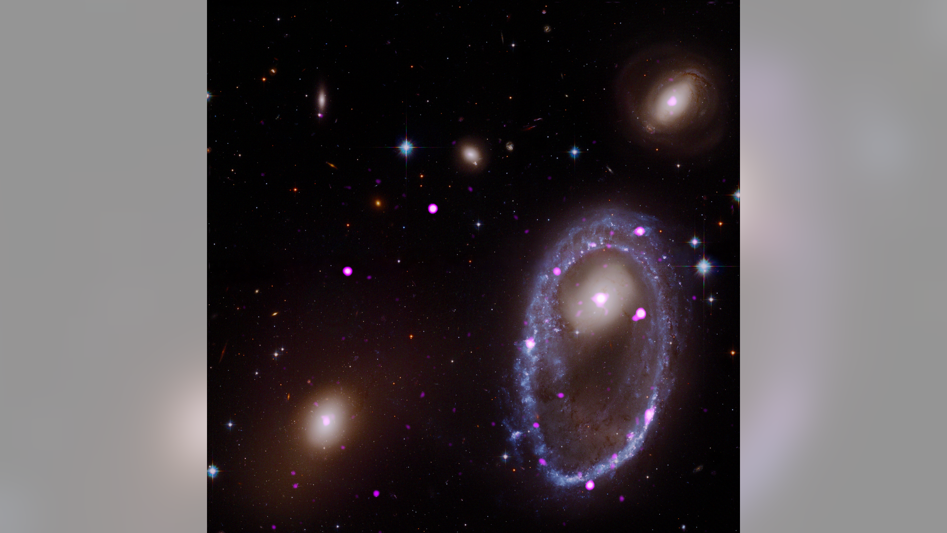 A composite image of the ring galaxy AM 0644-741. The image includes X-ray data from the Chandra X-ray Observatory (purple) and optical data from NASA's Hubble Space Telescope (red, green and blue). The galaxy AM 0644 is located in the lower right.