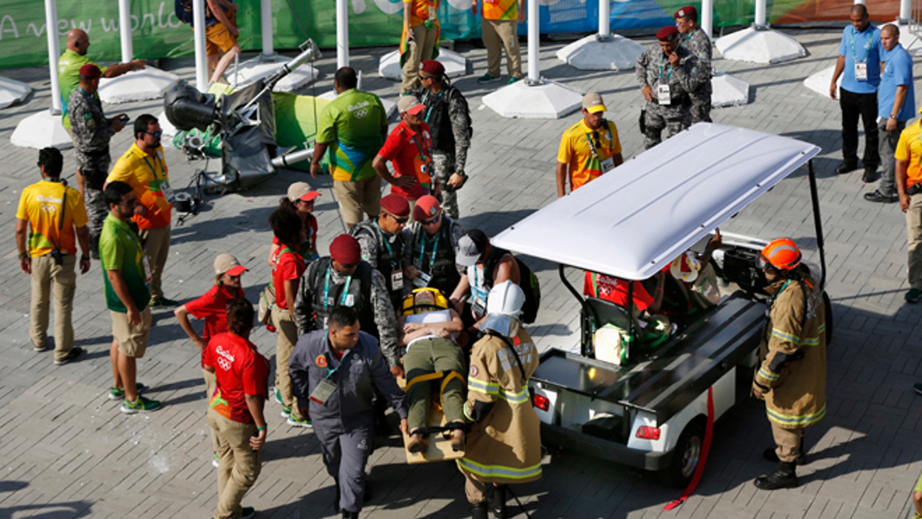 An injured woman is taken away on a backboard after being struck by an overhead television camera, laying top left, that fell from the wires suspending it over Olympic Park during the Summer Games in Rio de Janeiro, Brazil, Monday, Aug. 15, 2016.