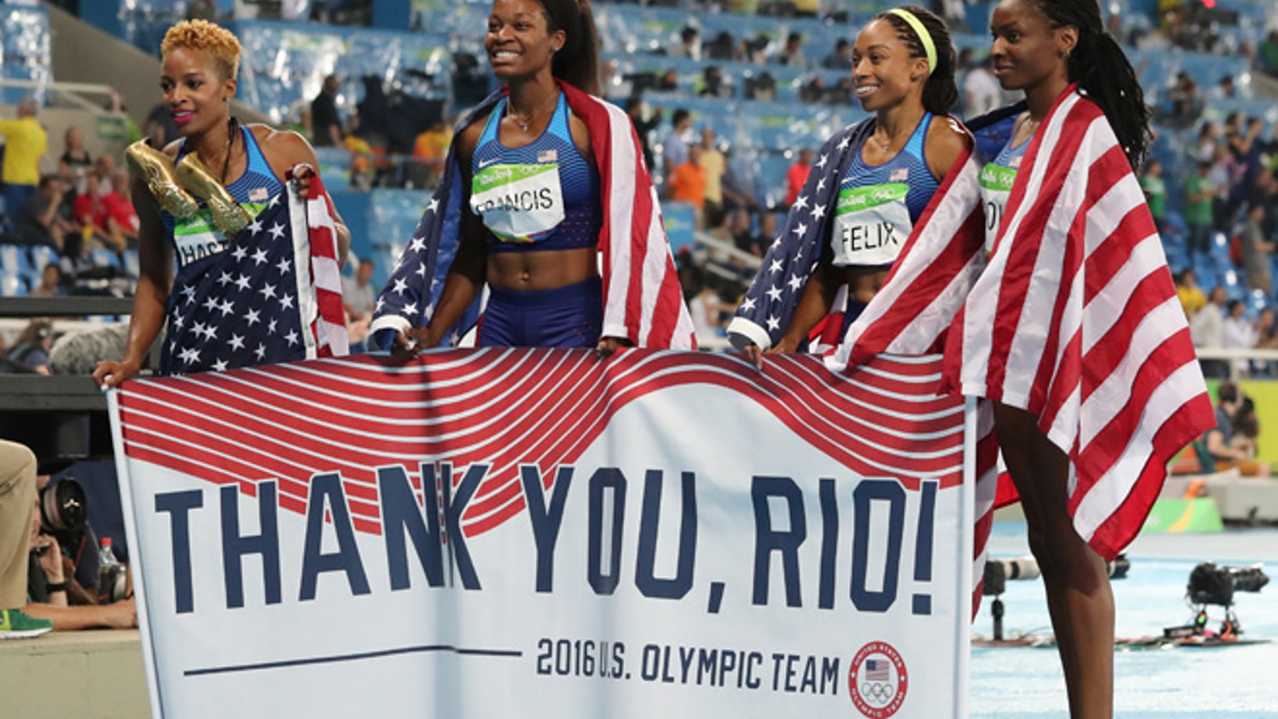 United States' Courtney Okolo, Natasha Hastings, Phyllis Francis and Allyson Felix hold a sign and wear their nation's flag after winning the gold in the women's 4x400 meter relay during athletics competitions at the Summer Olympics inside Olympic stadium in Rio de Janeiro, Brazil, Saturday, Aug. 20, 2016.