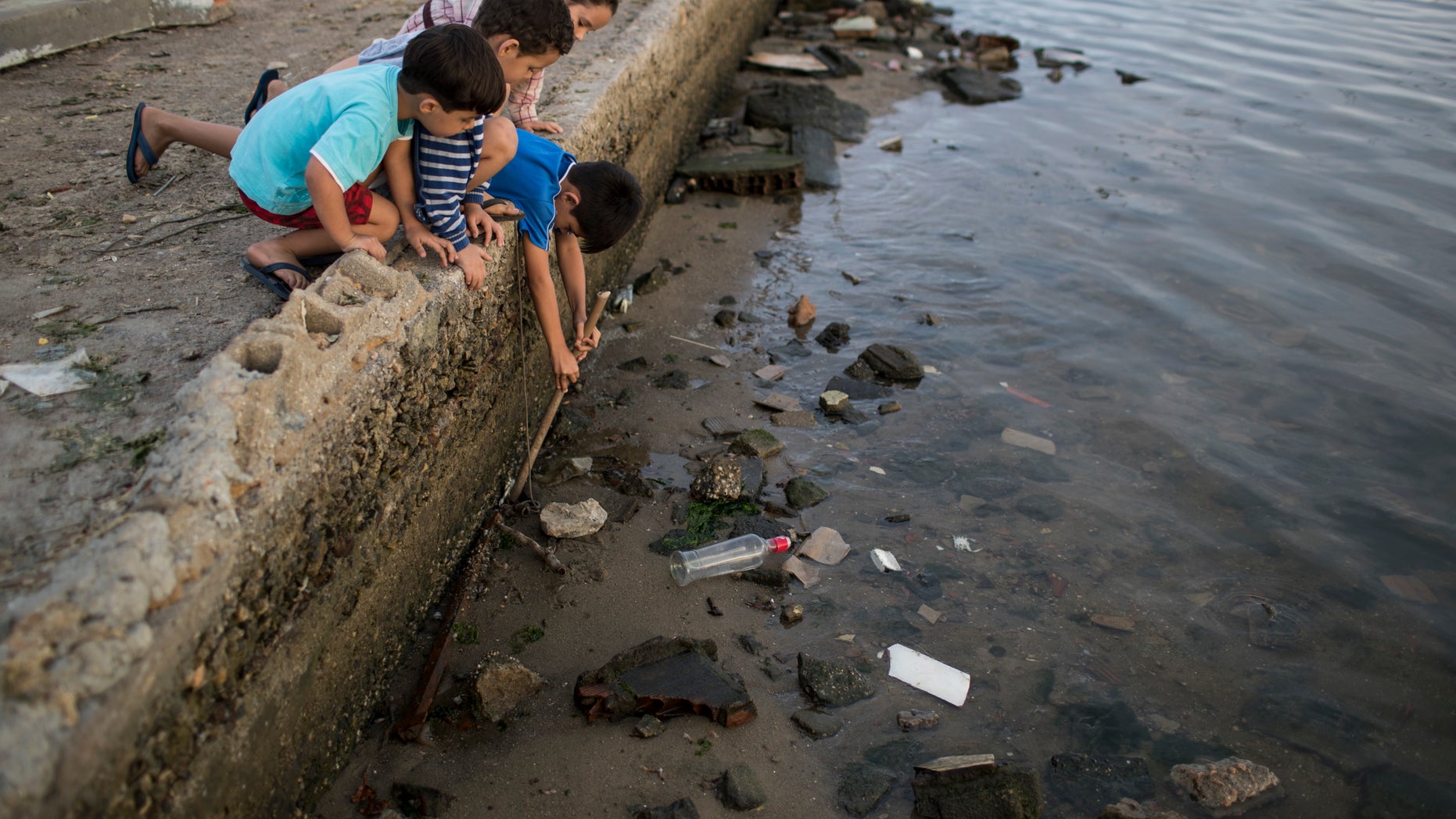 Children try to catch a crab as they play on the polluted shore of Guanabara Bay in Rio de Janeiro, Brazil, Saturday, July 30, 2016. In Rio, the main tourist gateway to the country, a centuries-long sewage problem that was part of Brazilâs colonial legacy has spiked in recent decades in tandem with the rural exodus that saw the metropolitan area nearly double in size since 1970. (AP Photo/Felipe Dana)