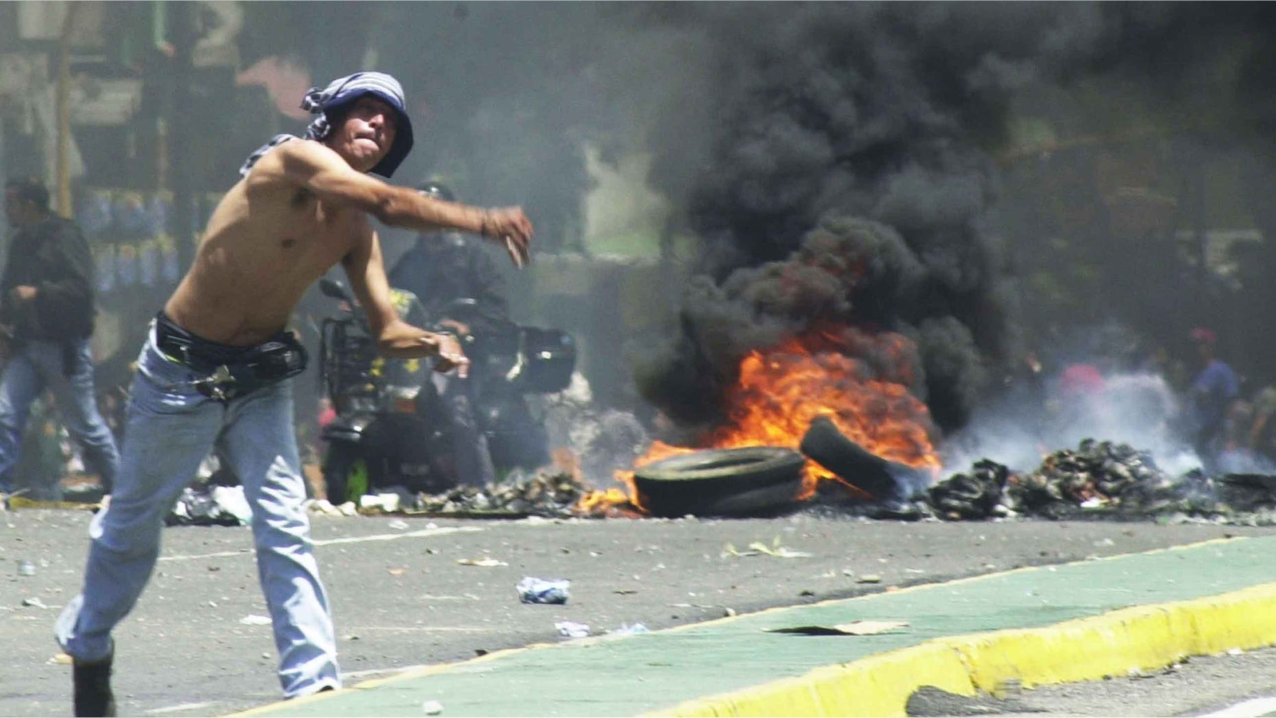 CARACAS, VENEZUELA - JULY 31: A supporter of President Hugo Chavez throws stones at riot police July 31,2002 in downtown Caracas, Venezuela. Venezuelan police fired tear gas and used water canons to disperse Chavez's supporters and foes who clashed outside the Venezuela's Supreme Court. The court is expected rule on the fate of four alleged military coup plotters. (Photo by Oscar Sabetta/Getty Images)