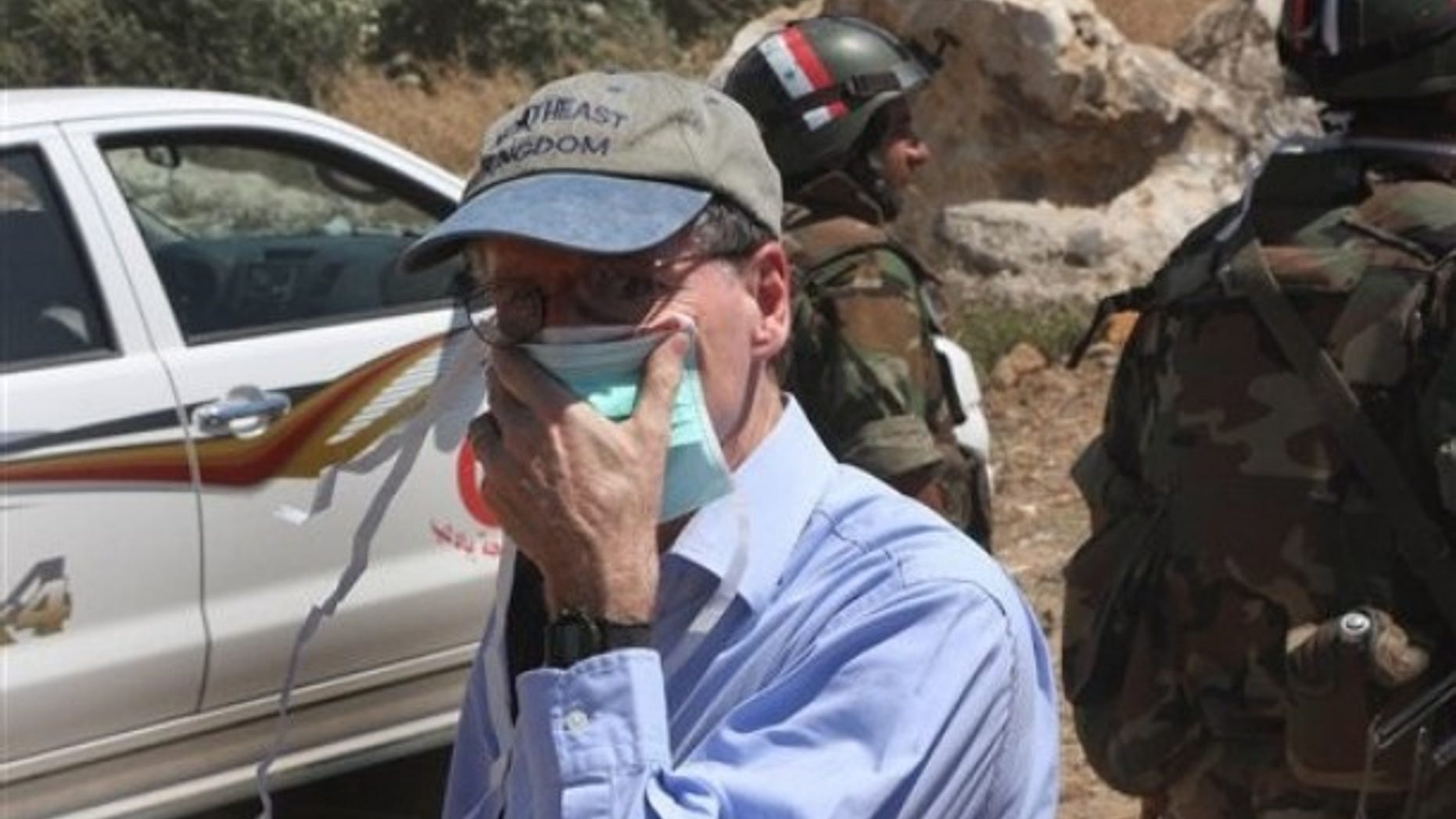 In this photo taken during a government-organized tour for foreign diplomats and the media, US ambassador in Syria Robert Ford, covers his nose from the smell of the dead bodies during his visit with other foreign diplomats to a mass grave, in Jisr el-Shughour, north of Syria, on Monday, June 20, 2011.