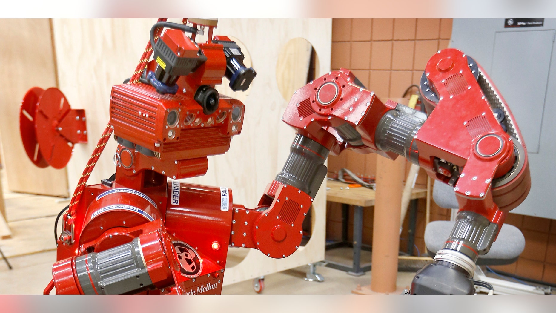 In this Wednesday, Dec. 11, 2013 photo, the CMU Highly Intelligent Mobile Platform robot, known as CHIMP, (CMU Highly Intelligent Mobile Platform) is put through some paces as it is switching the hold of a fire hose from one grasping unit to another at the National Robotics Engineering Center in Pittsburgh. Carnegie Mellon researchers are testing the new search-and-rescue robot that will compete in the U.S. Defense Department's upcoming national robotics competition in Florida. Competitors from other schools and companies will be vying for a $2 million U.S. Defense Department prize. (AP Photo/Keith Srakocic)