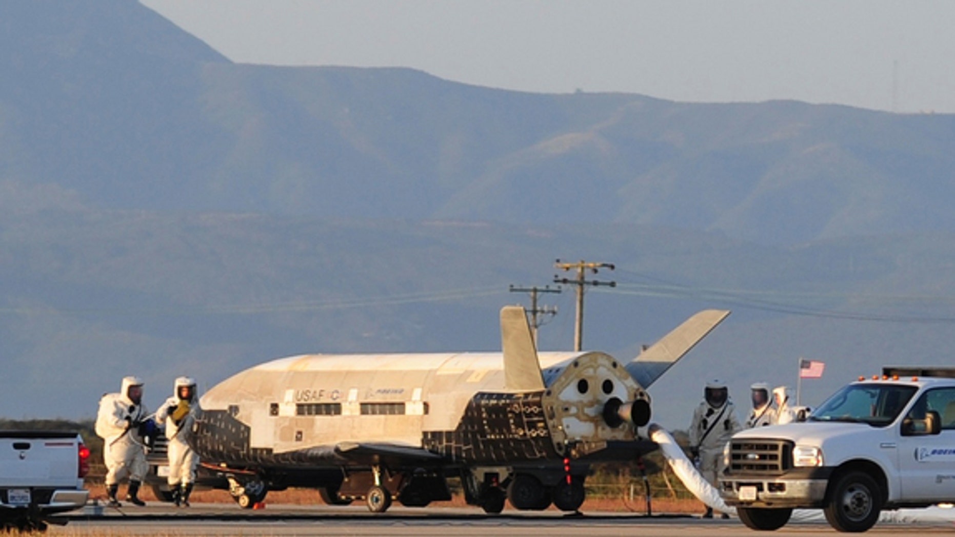 Technicians inspect the military X37-B space plane after its June 2012 landing, which completed the vehicle's second trip to orbit.