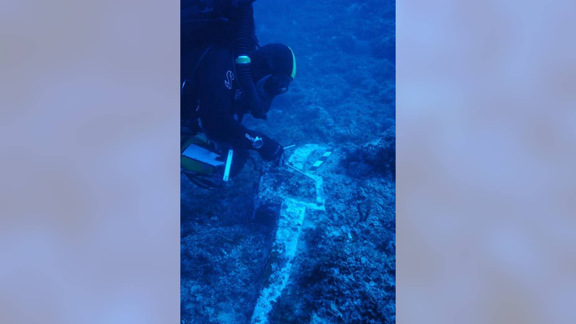 Here a researcher examines the anchor of what may be the Antikythera wreck or another wreck nearby. They are uncertain because they used Costeau's Antikythera expedition videos to gauge where to anchor their boat. Since some of the shots in the