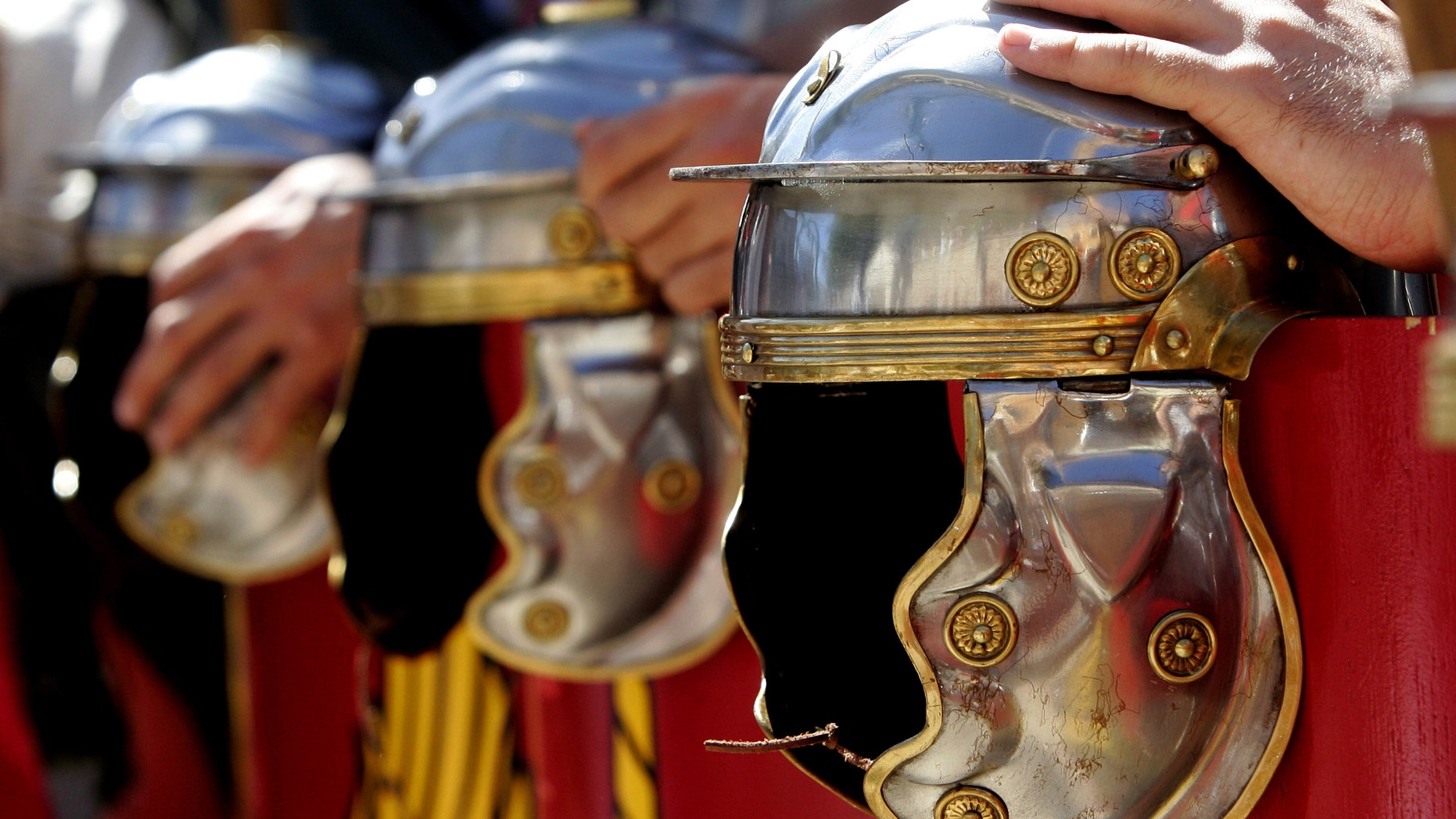 File photo - Actors, dressed as a Roman pretorian guards, hold their helmets at a parade during a show reviving the ancient Roman circus in the central Spanish village of Banos de Valdearados August 22, 2004. (REUTERS/Felix Ordonez)