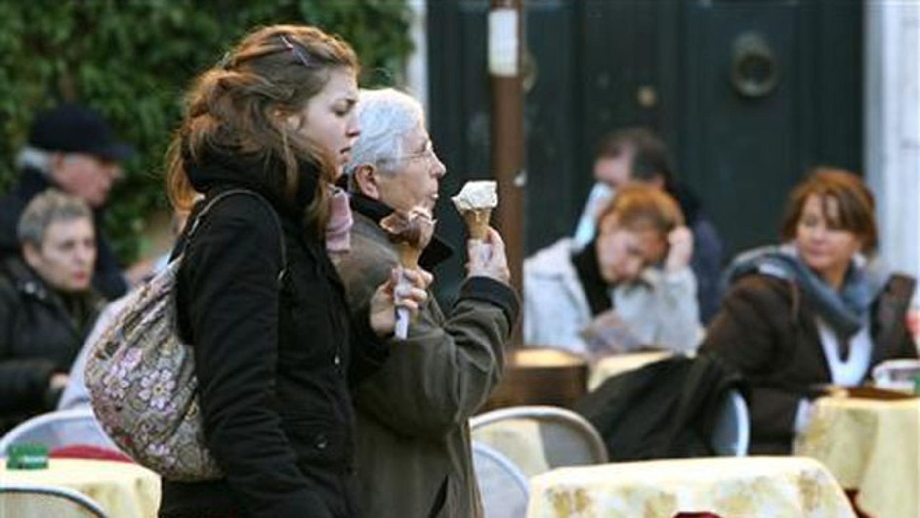 Italians eating gelato ice-cream while passing diners at Campo di Fiori in Rome. Tourist and other visitors can now face fines for snacking at the city's historic sites.