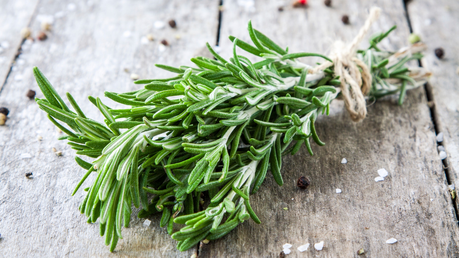 a bunch of fresh rosemary on a wooden background