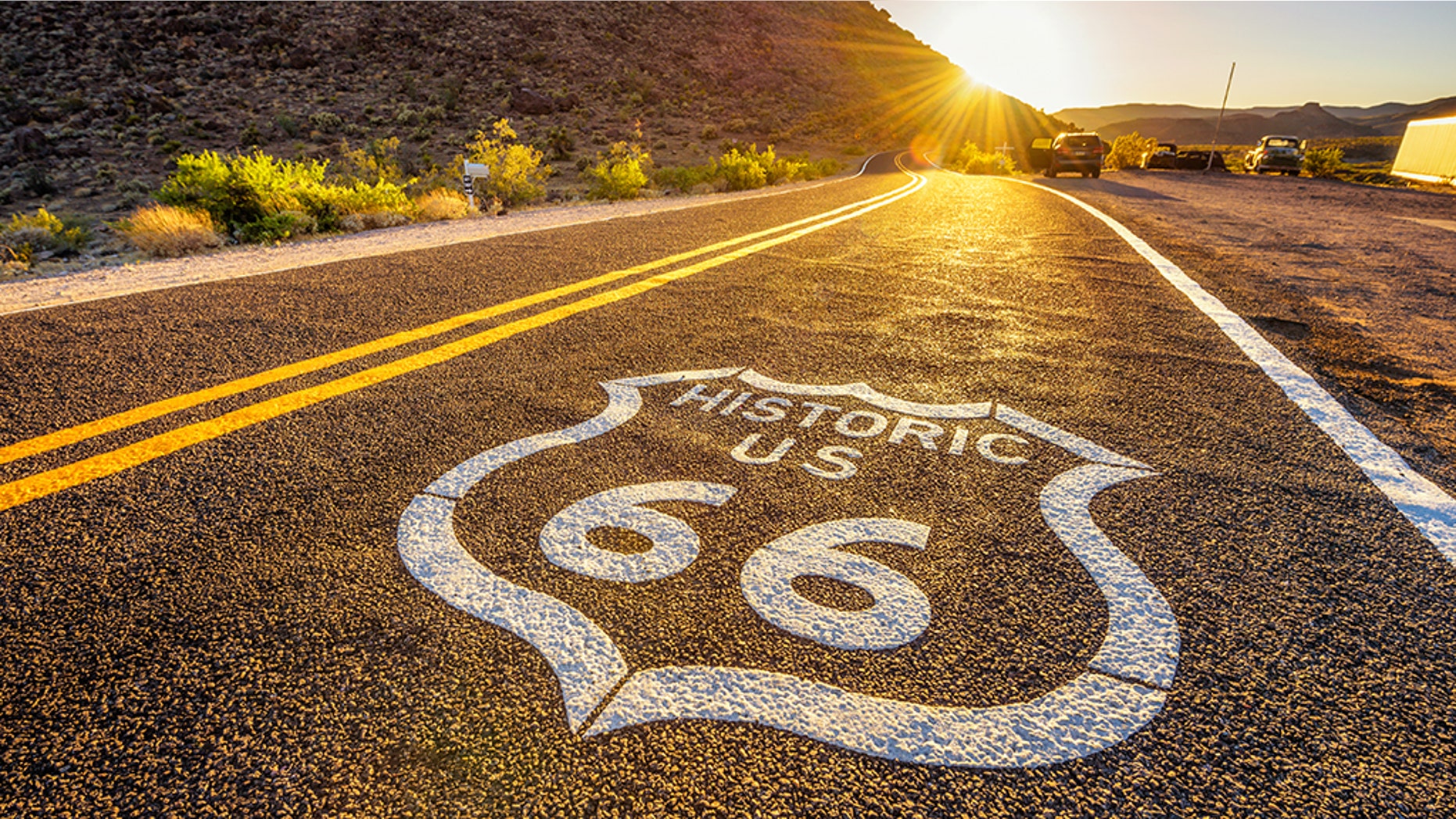Street sign on historic route 66 in the Mojave desert photographed against the sun at sunset